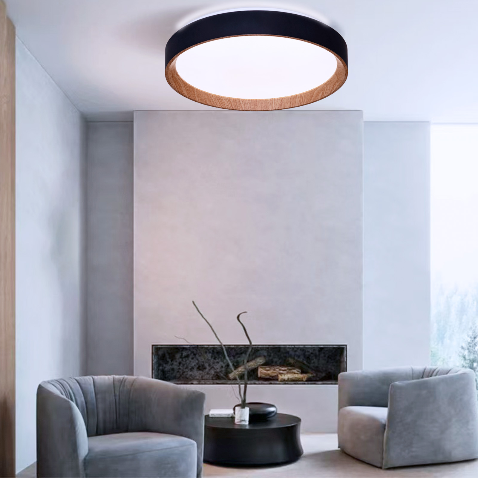 Una luz de techo redonda con un anillo exterior negro y un anillo interior de vetas de madera. Dos sillones grises.