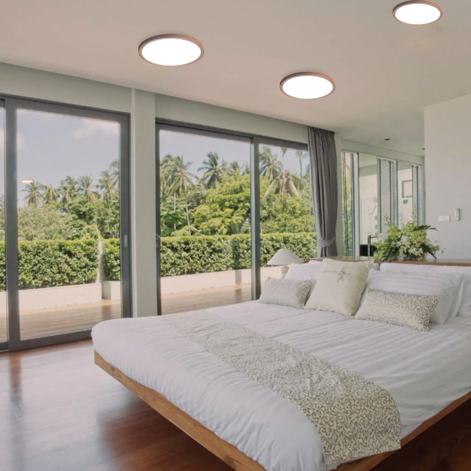 Dormitorio con grandes ventanas con vistas a un paisaje verde. Se ven tres luces de techo marrones.