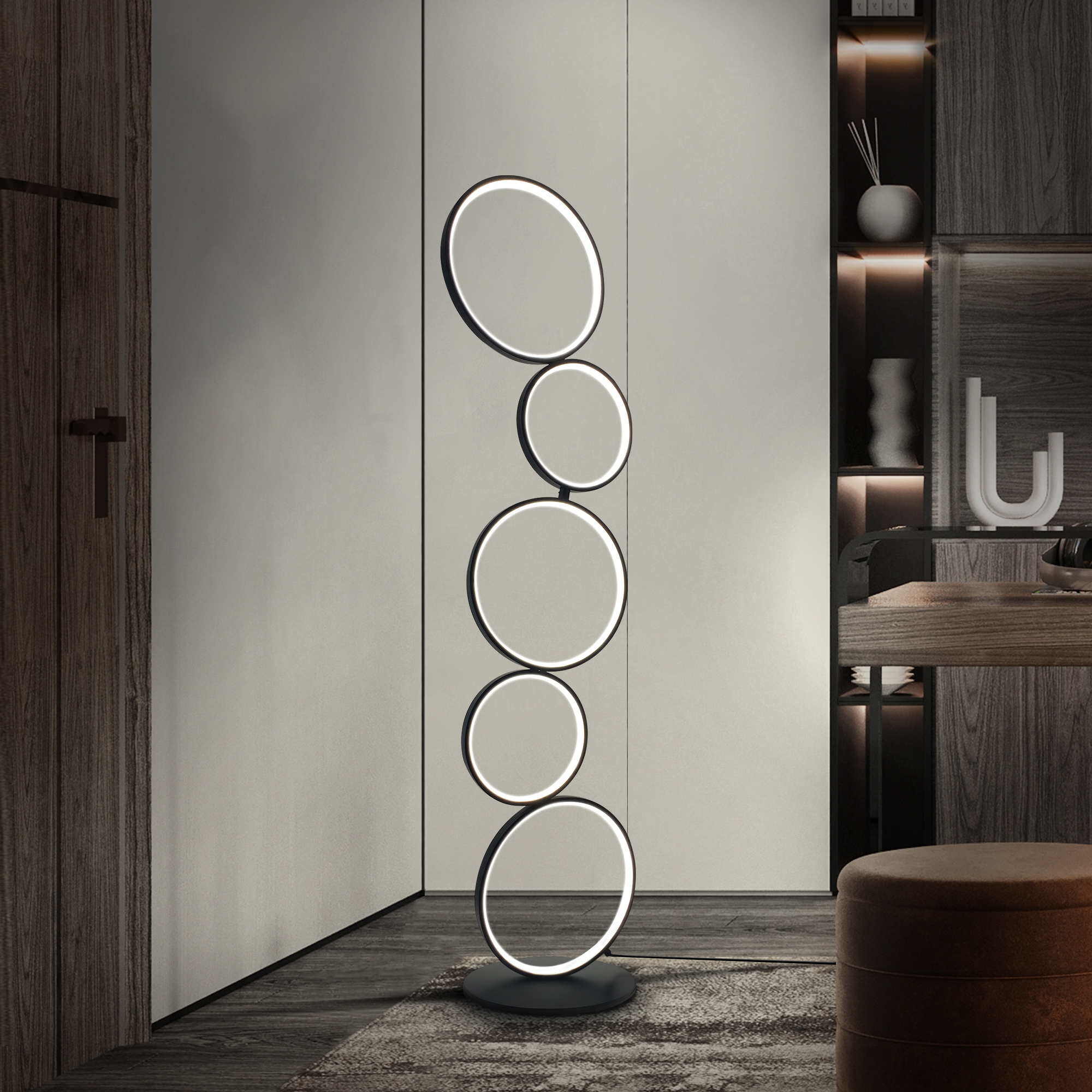 Una lámpara de pie moderna con cinco luces circulares apiladas, de pie en una habitación con puertas de madera y un taburete.