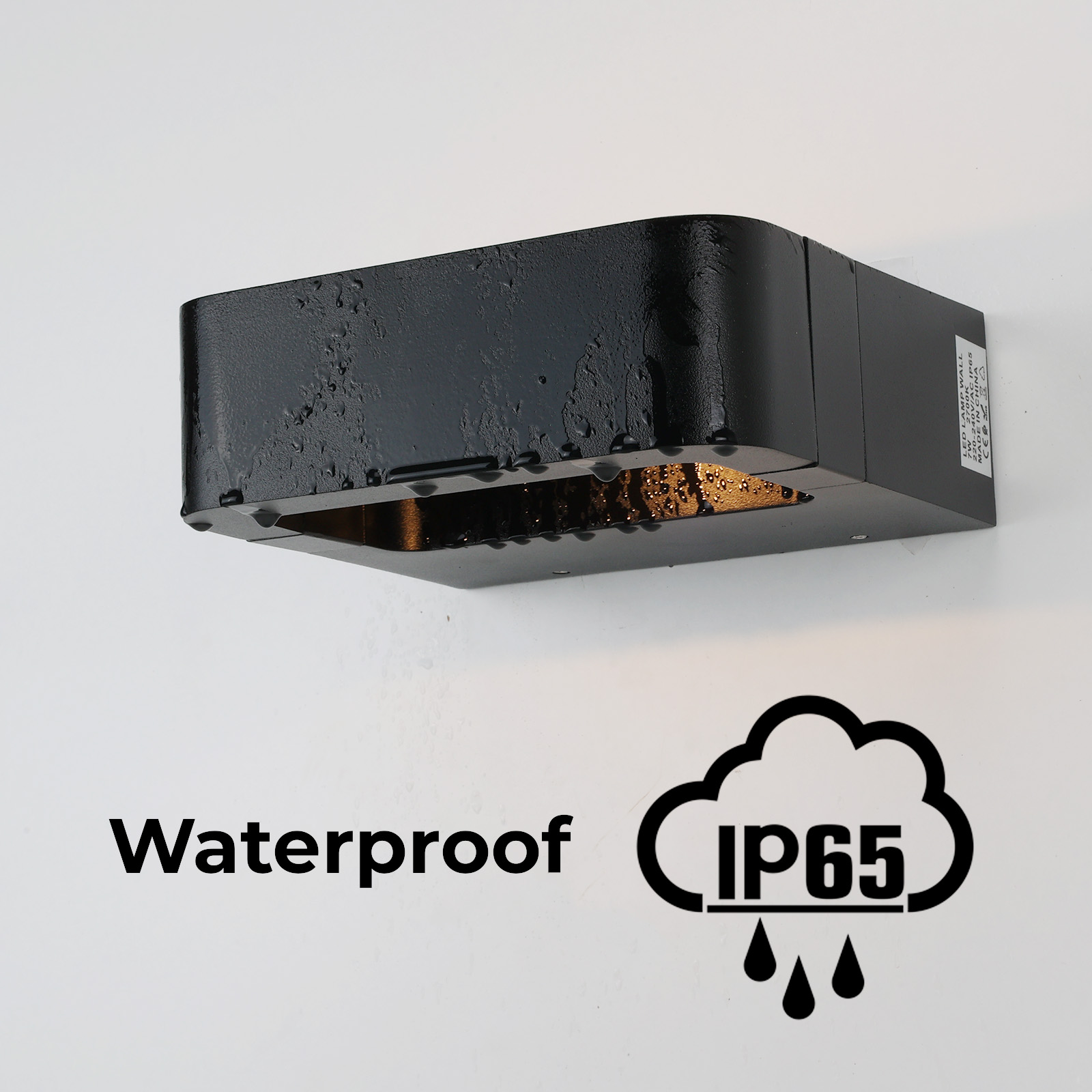 Una lámpara de pared exterior rectangular negra con la palabra "Waterproof" y el símbolo IP65, que muestra gotas de agua.