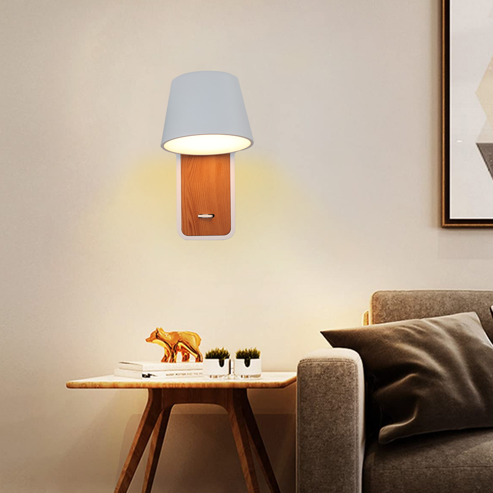 Lámpara de pared con pantalla gris y base de madera. Está en una pared blanca con una mesita y un sofá.