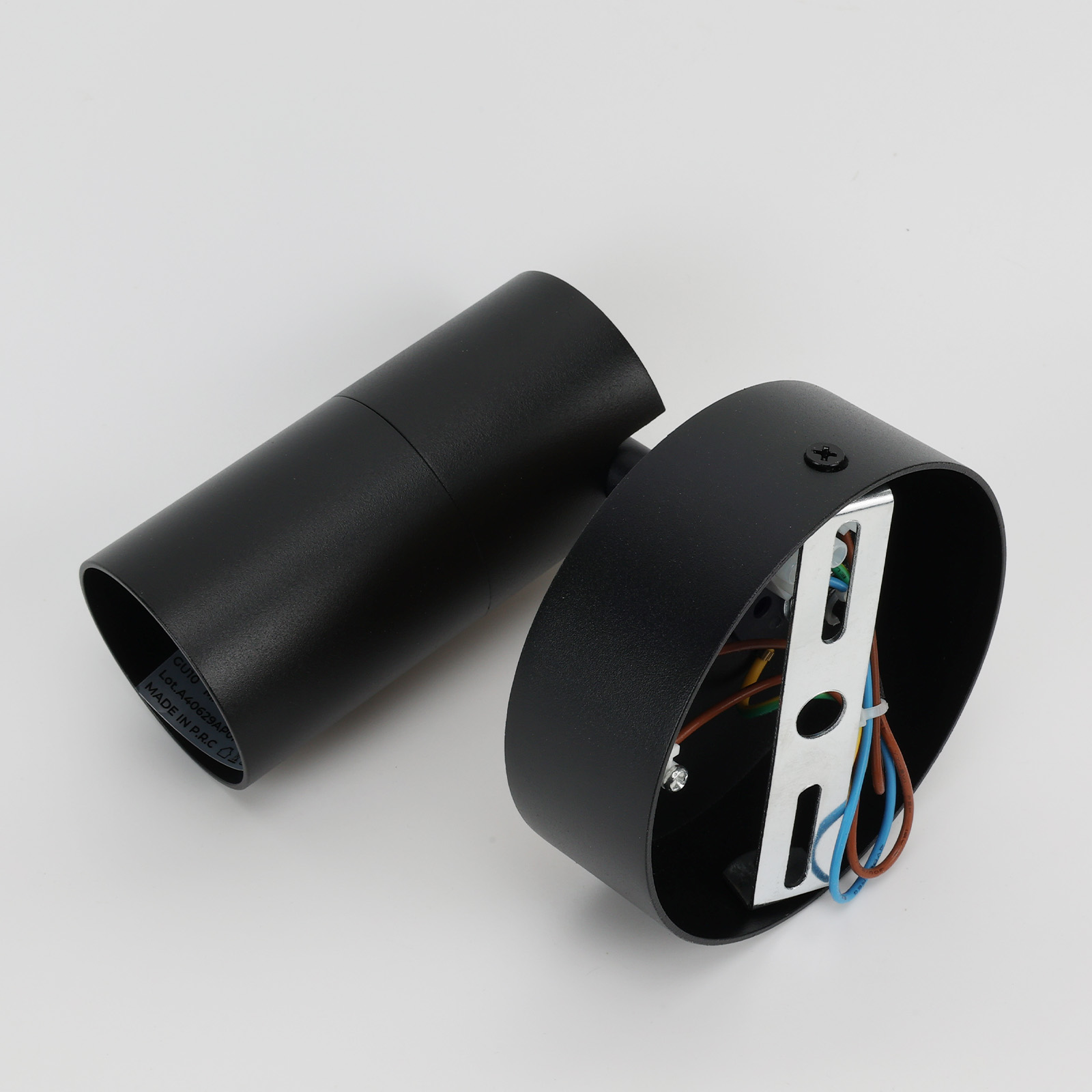 Foco negro desmontado. El cuerpo principal y la base con el cableado son visibles.