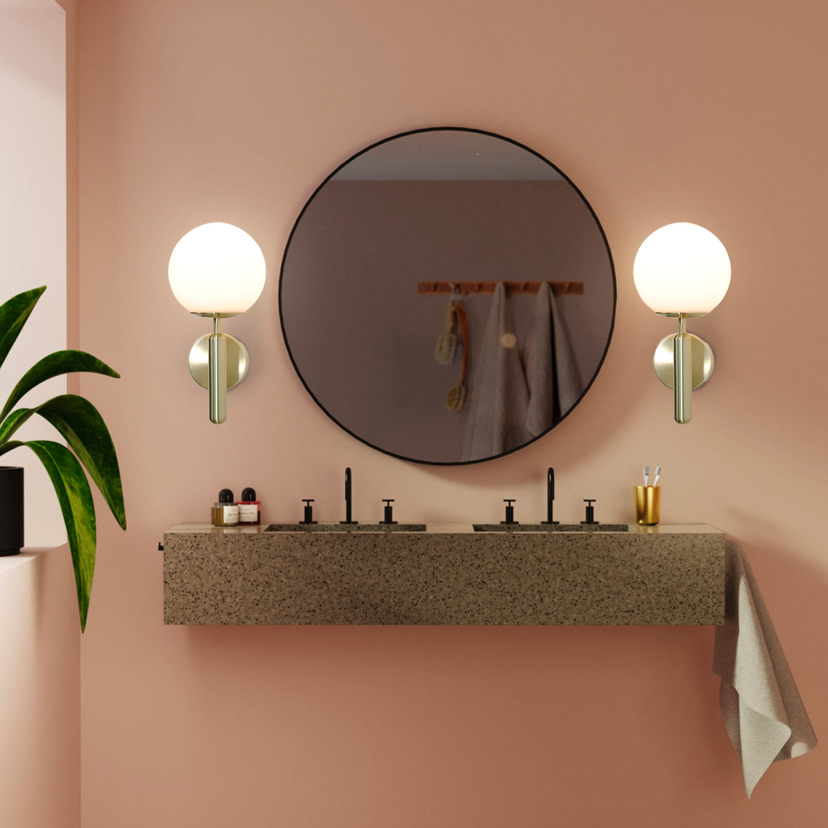 Una escena de baño con dos lámparas de pared doradas y un espejo redondo sobre un lavabo.