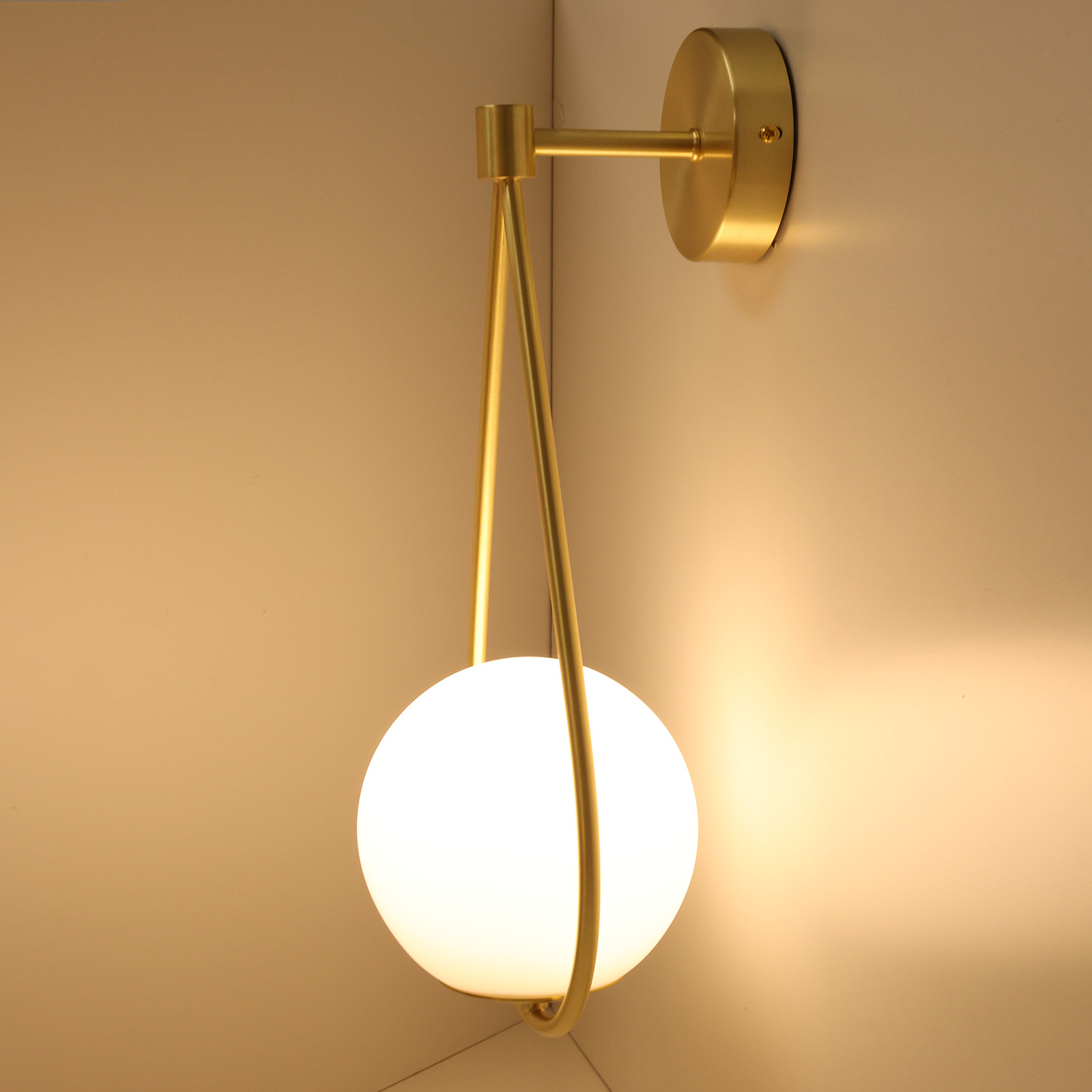 Una lámpara de pared dorada con una luz blanca en forma de globo en una esquina. Diseño moderno.