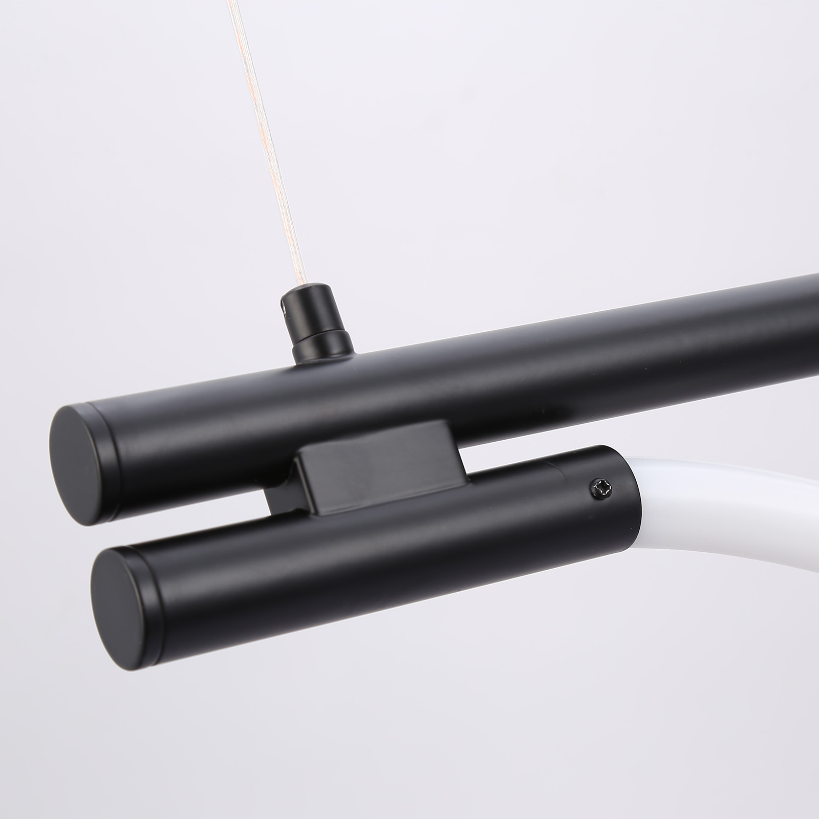Primer plano del punto de conexión de una lámpara colgante moderna, que muestra una barra de metal negro y un tubo curvo blanco.