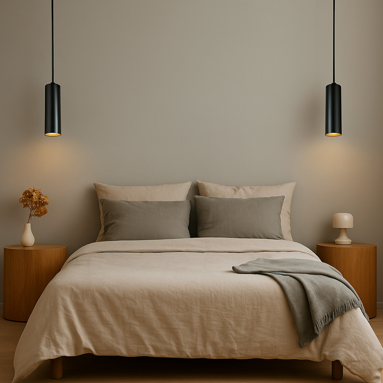 Dos lámparas colgantes cilíndricas negras cuelgan sobre una cama. Hay mesitas de noche y decoración.