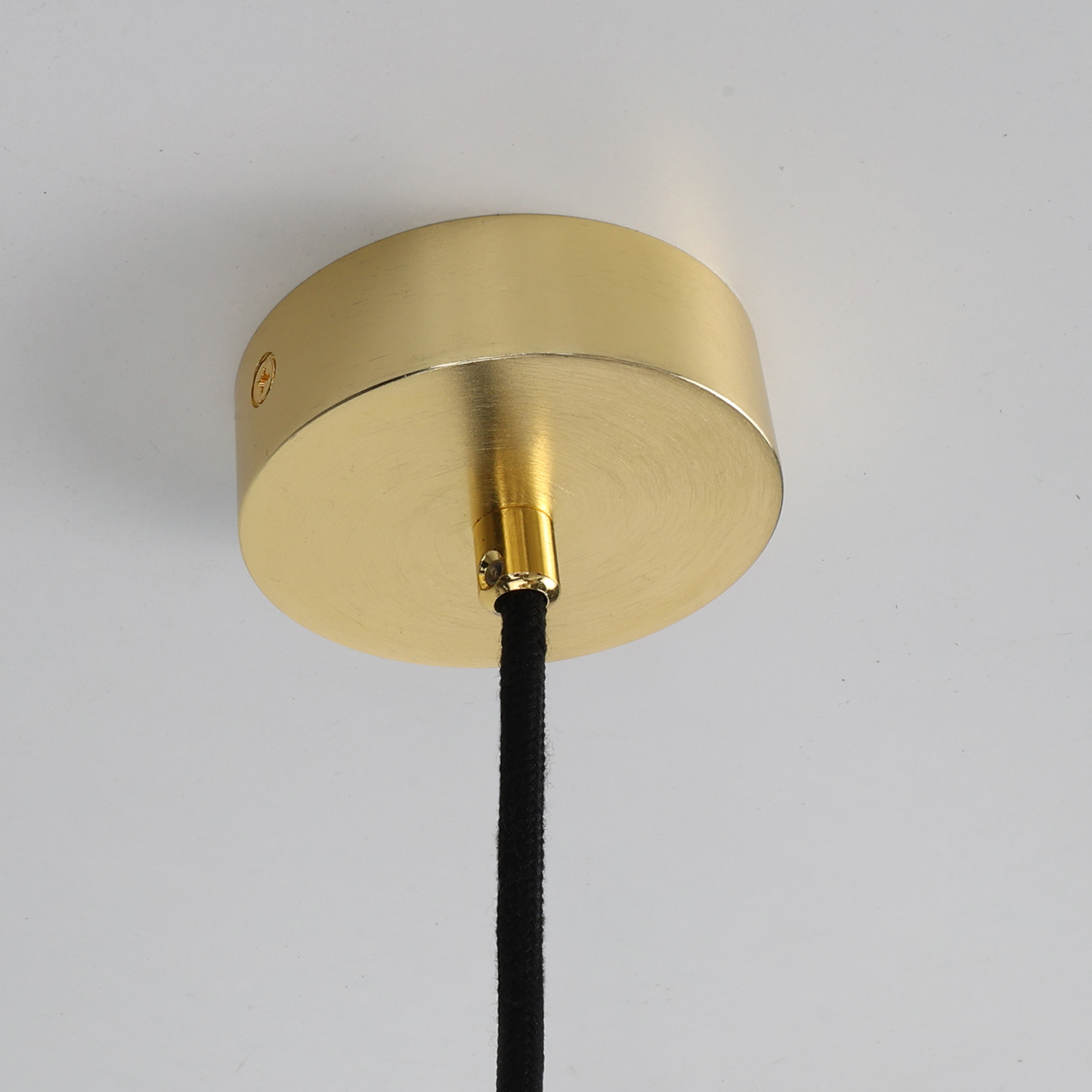 Un accesorio de luz de techo dorado. Un cable negro cuelga de él.