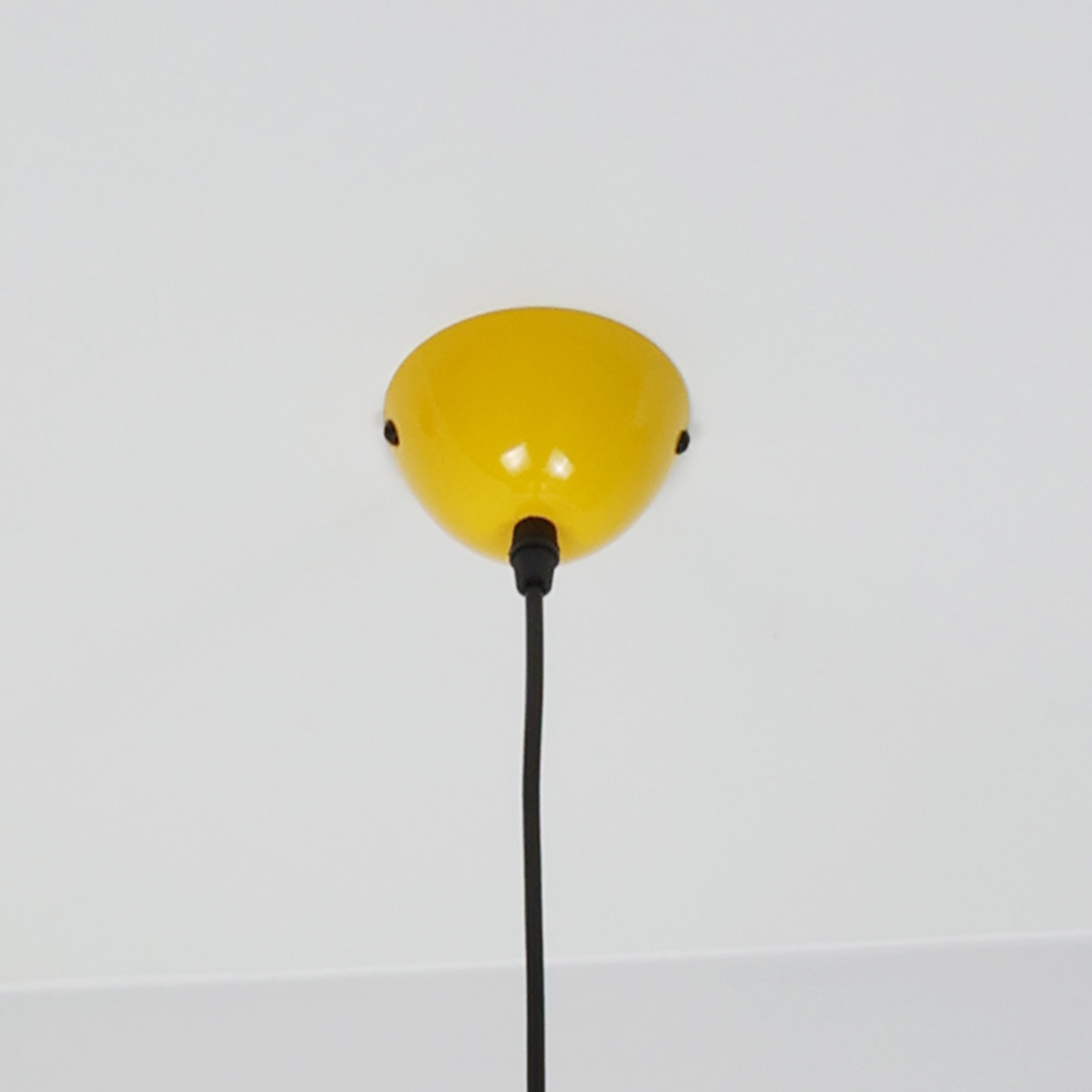 Un accesorio de techo amarillo con un cable negro colgando de él.