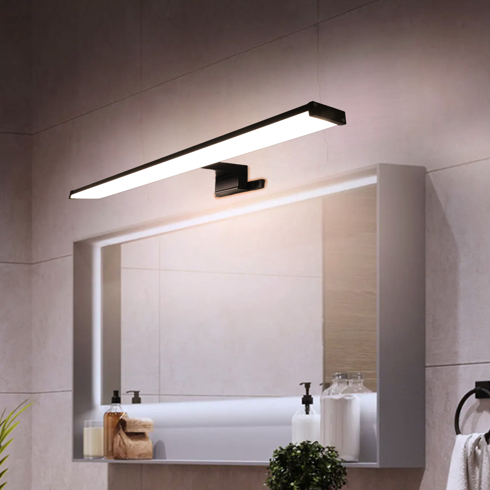 Una lámpara LED negra para baño sobre un espejo, en una pared de azulejos beige.