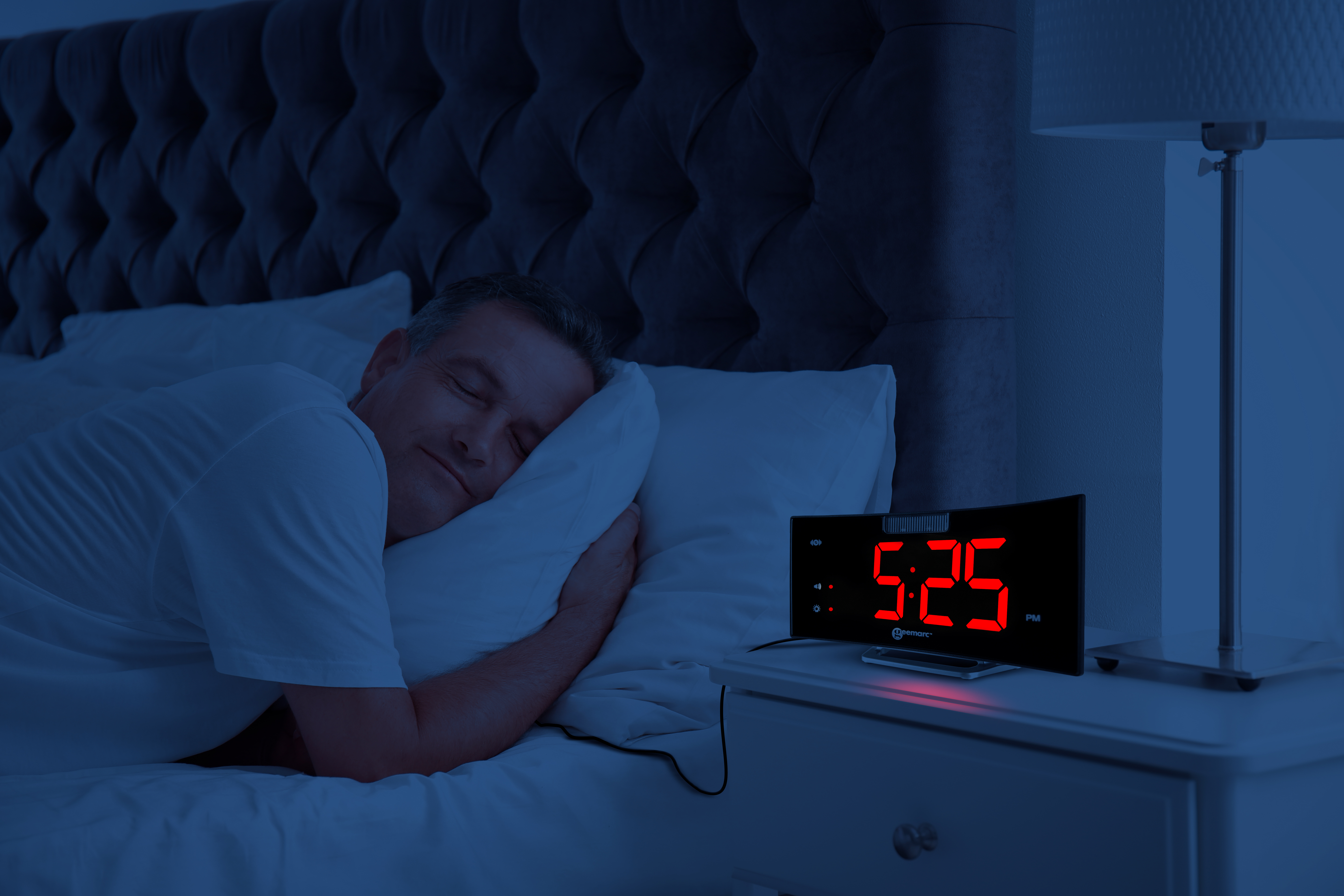 Un uomo dorme a letto con un orologio sul comodino che mostra le 5:25 del mattino.