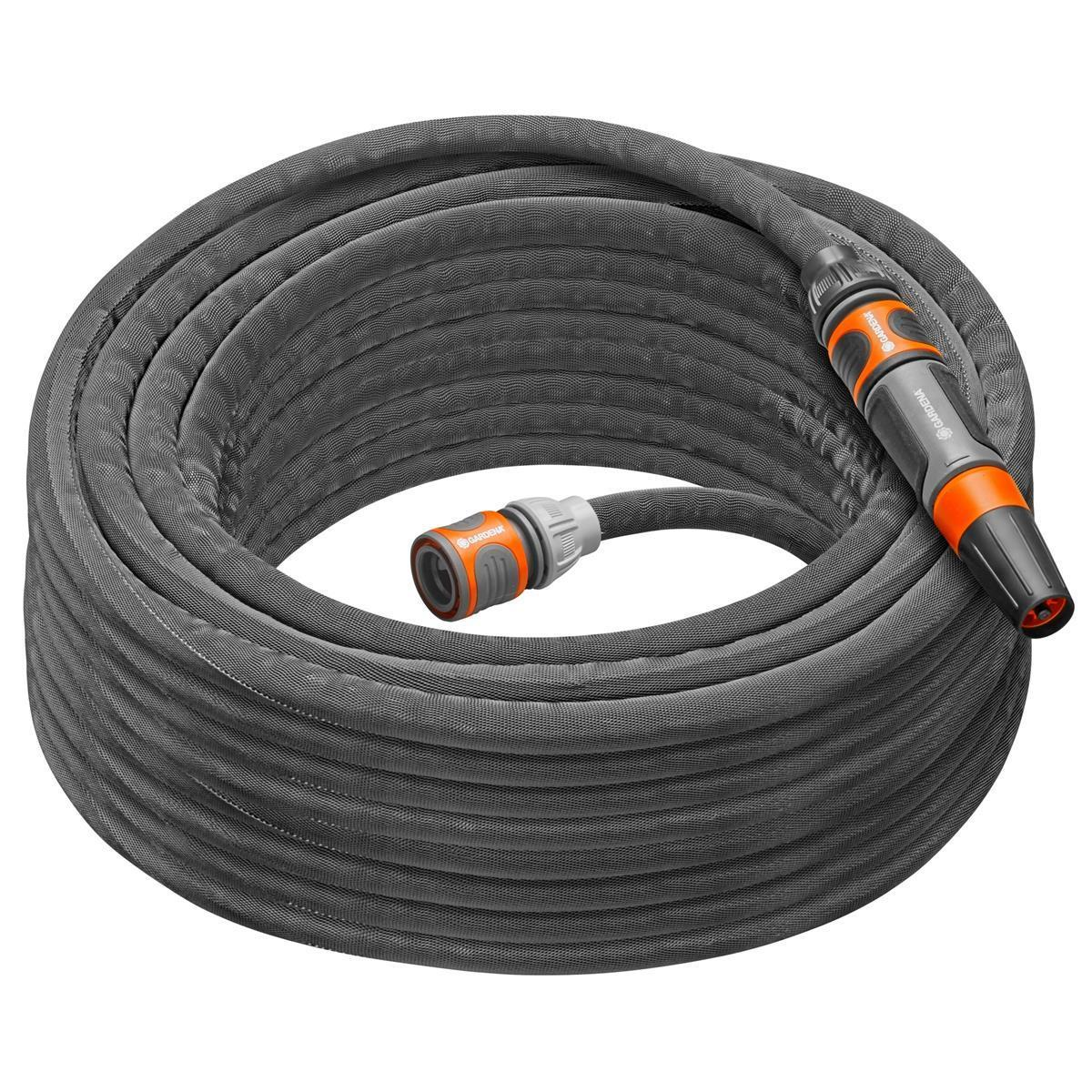 Un tubo da giardino grigio arrotolato con un connettore e un ugello. Il tubo è su uno sfondo scuro.