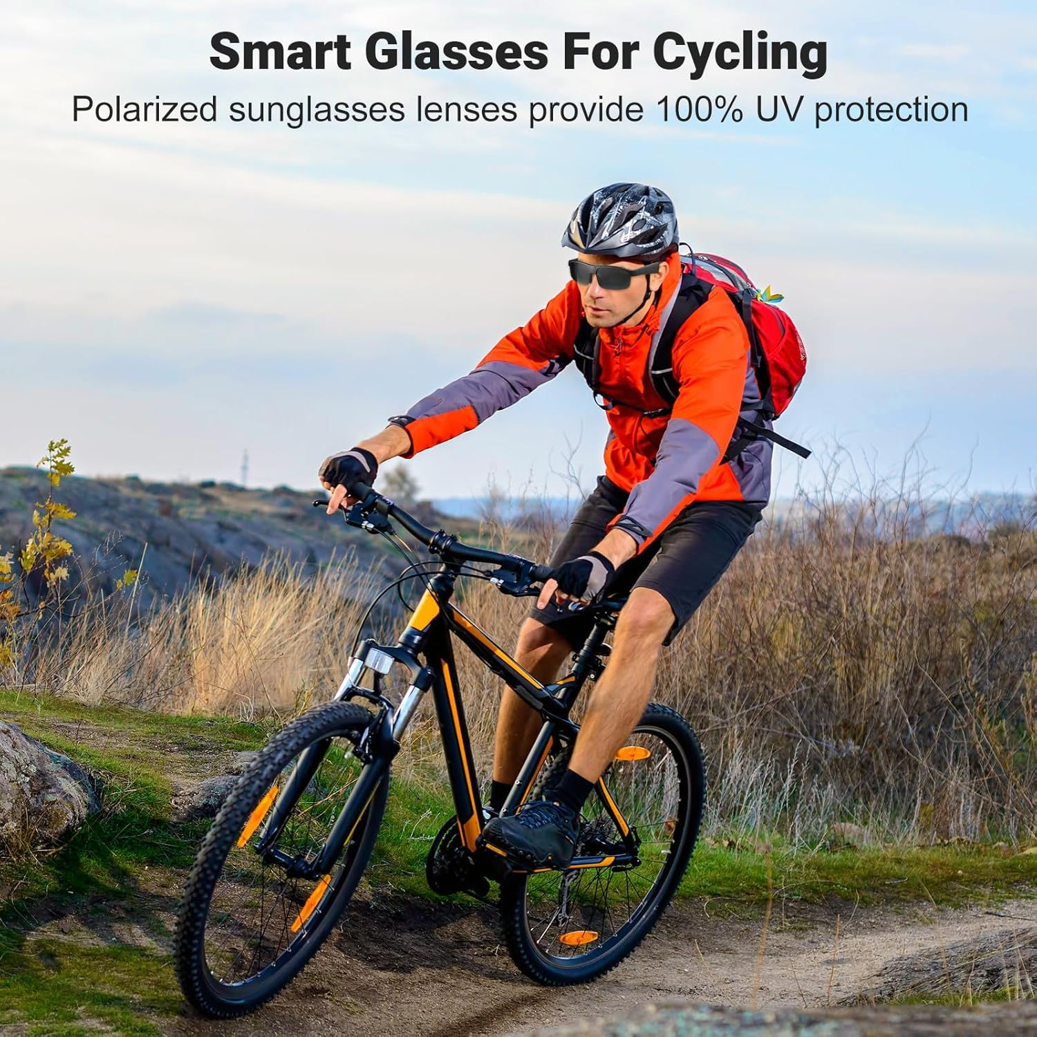 Hombre montando en bicicleta con gafas inteligentes. Las gafas son negras. Lleva casco, chaqueta roja y va por un camino de tierra.