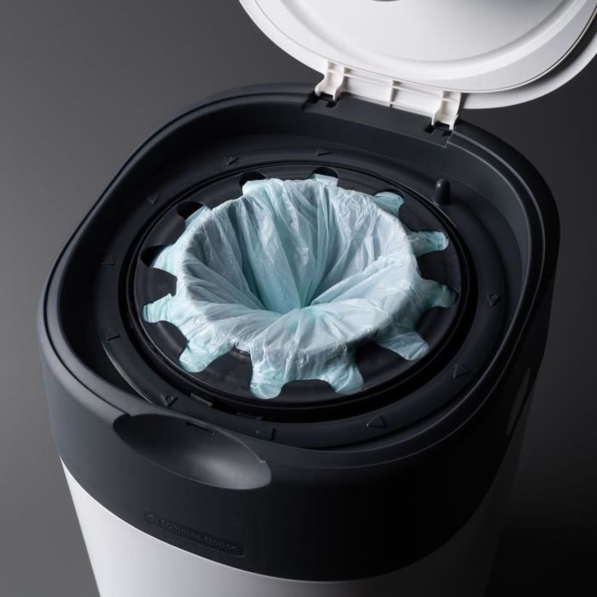 Ein geöffneter Windeleimer mit einem blauen Plastikbeutel darin. Der Eimer hat einen grauen Deckel und einen weißen Korpus.
