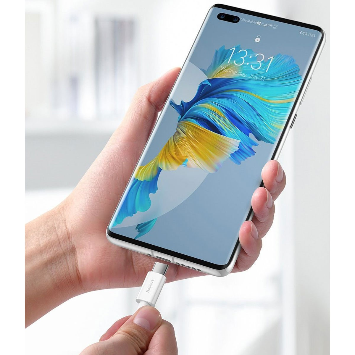 Hand houdt telefoon vast met oplaadkabel. Scherm toont tijd en datum.