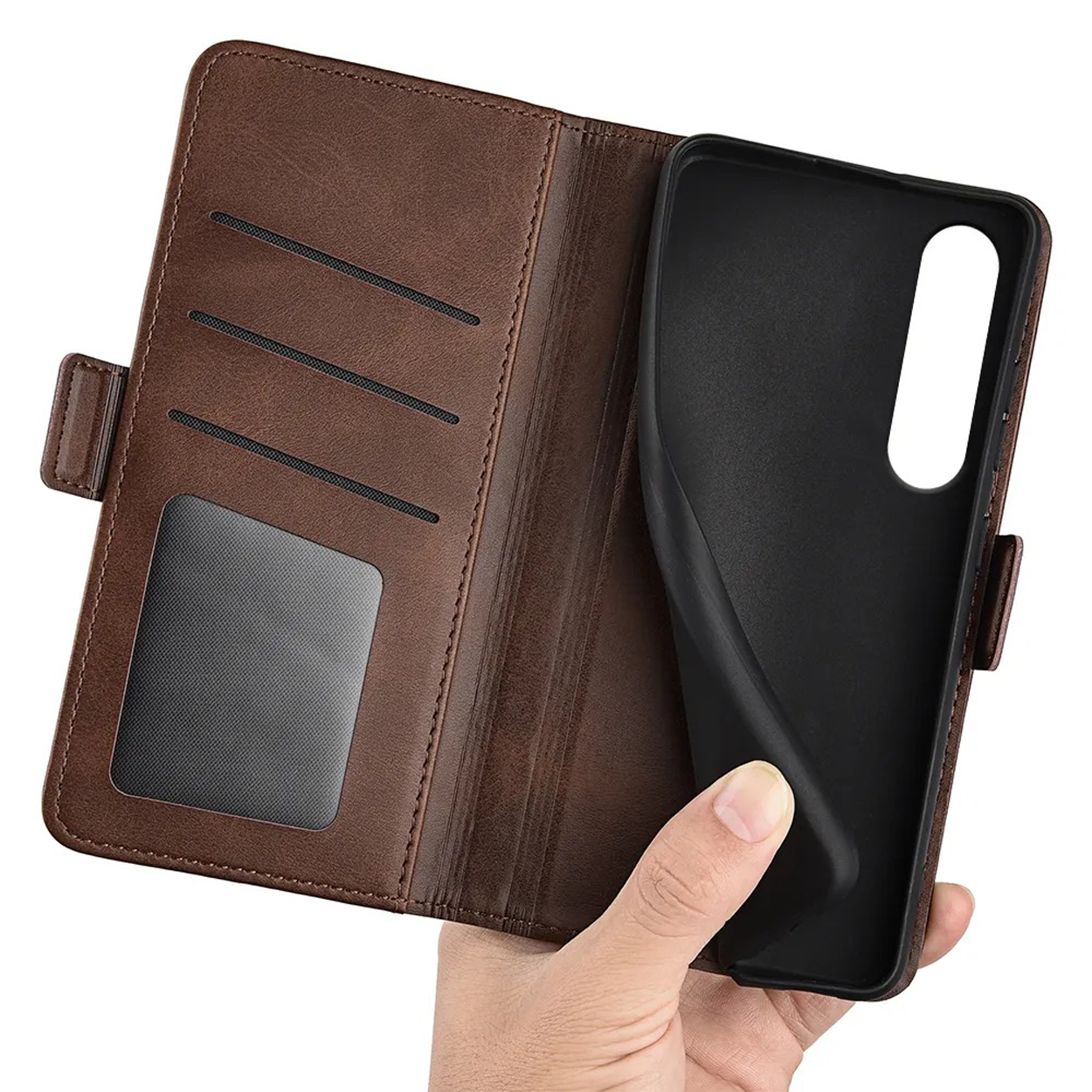 Hand houdt bruine leren telefoonhoes vast, open. Binnenkant met sleuven.