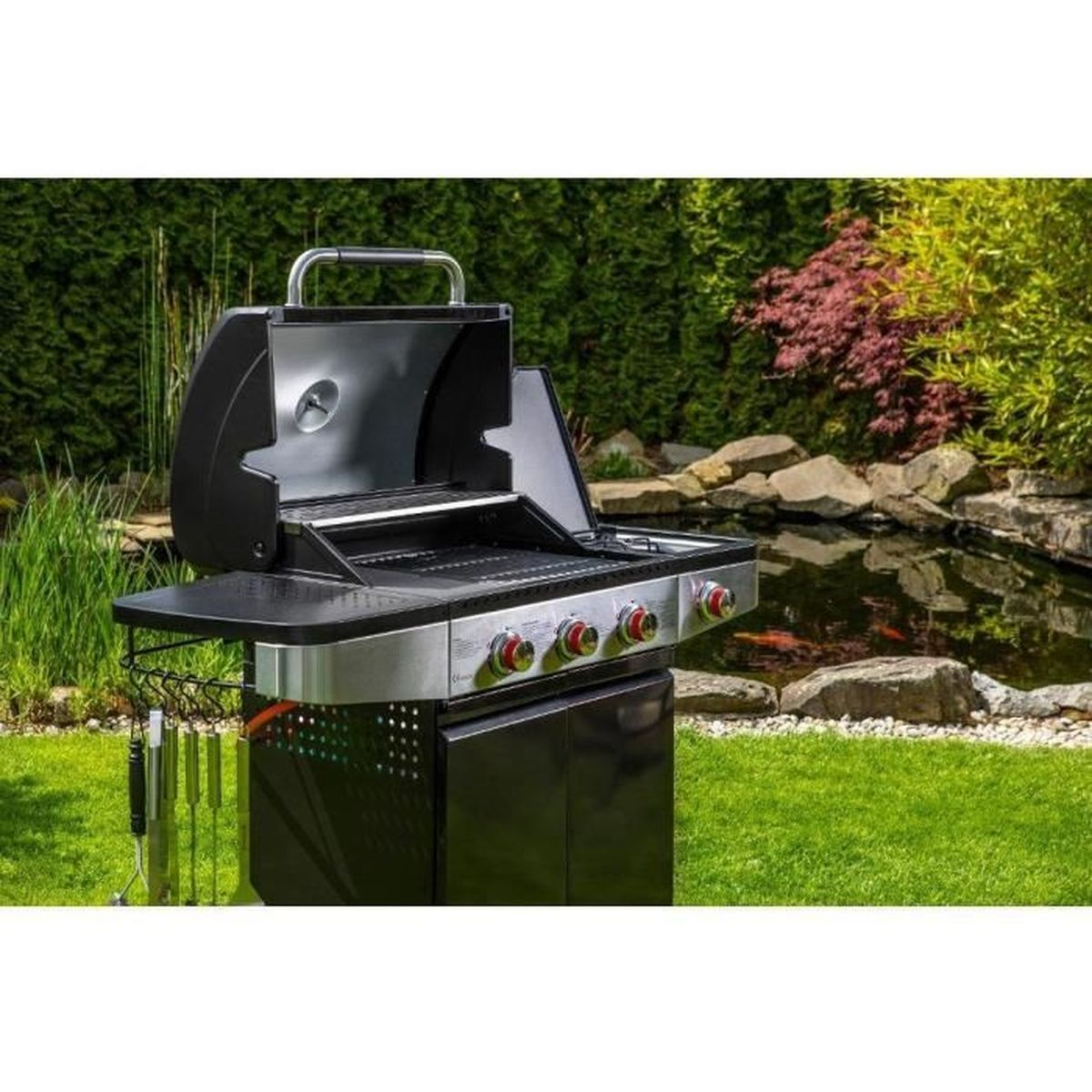 Ein schwarzer Gasgrill befindet sich in einem Garten, mit einem See und grünen Bäumen im Hintergrund.