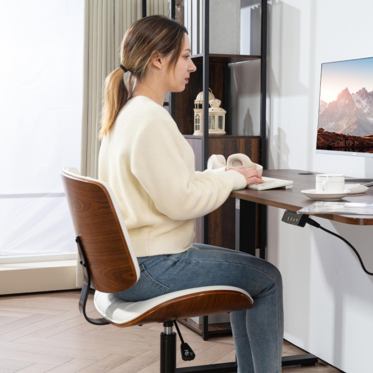 Eine Frau sitzt an einem Schreibtisch und tippt auf einer Tastatur. Sie befindet sich in einer modernen Büroumgebung.