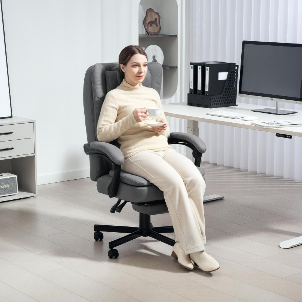 Eine Frau sitzt in einem grauen Bürostuhl und hält eine Tasse in einer hellen Büroumgebung.