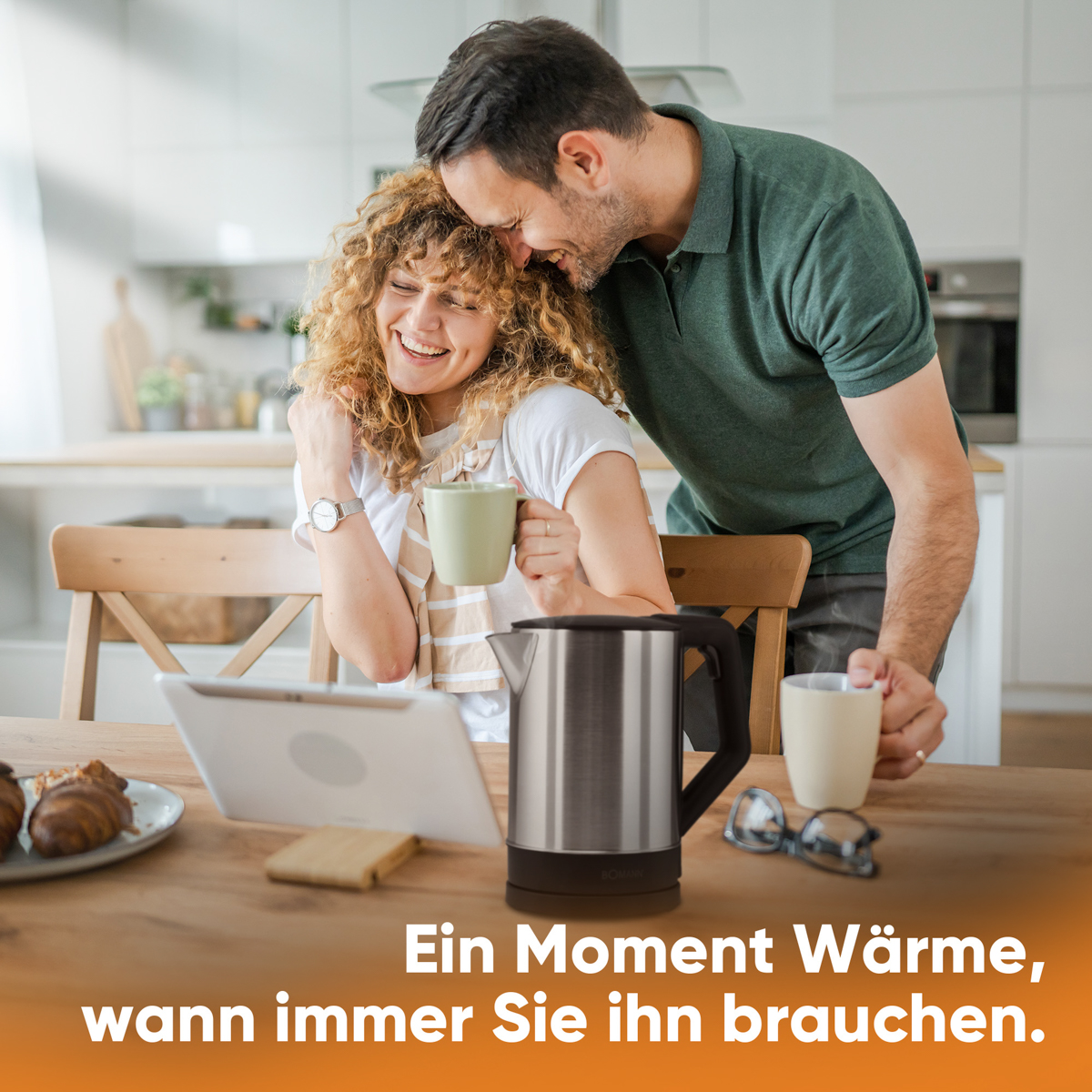 Para obejmuje się przy stole. Na stole czajnik, tablet, kubki i okulary.