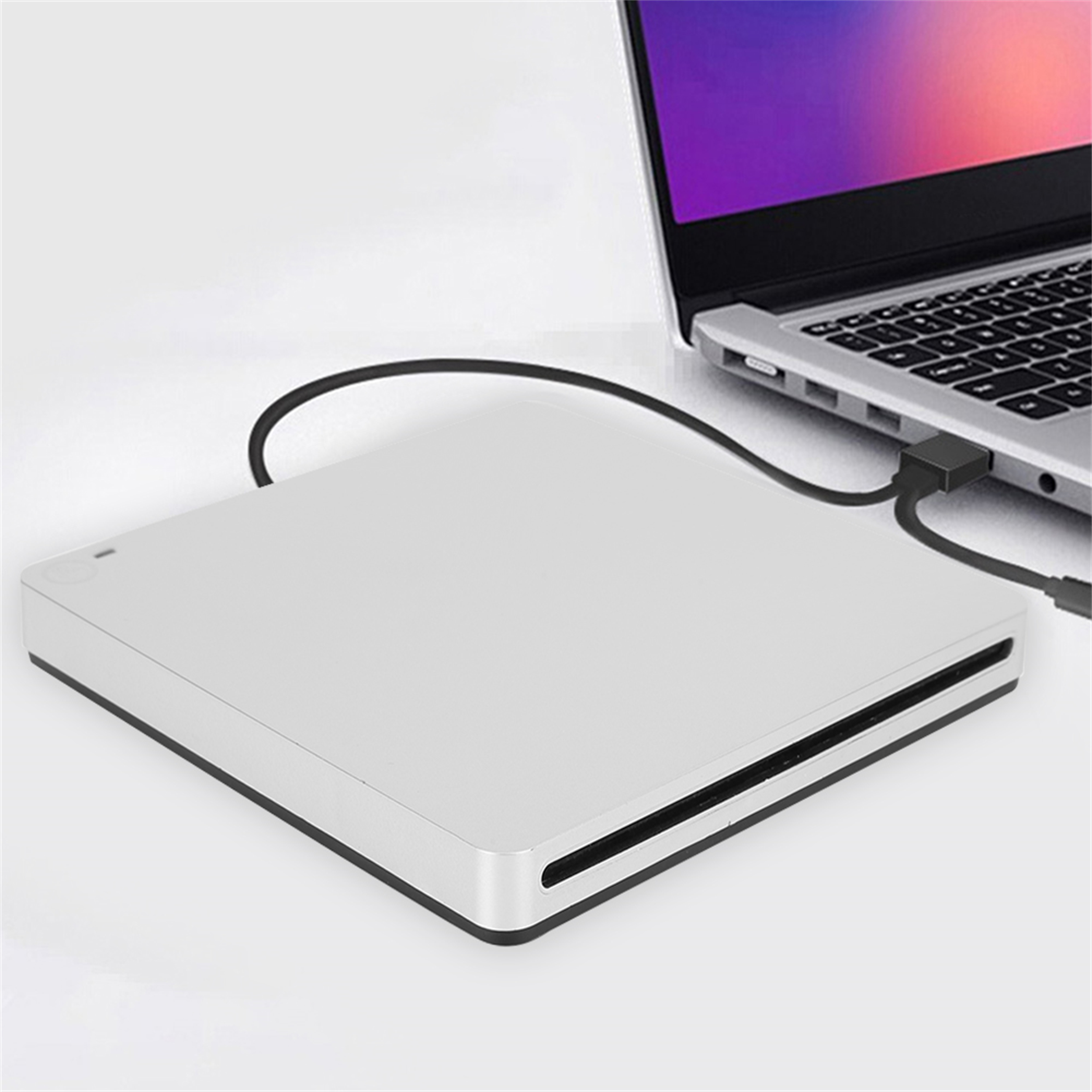 Eine silberne externe Festplatte, die über ein schwarzes USB-Kabel mit einem Laptop verbunden ist.