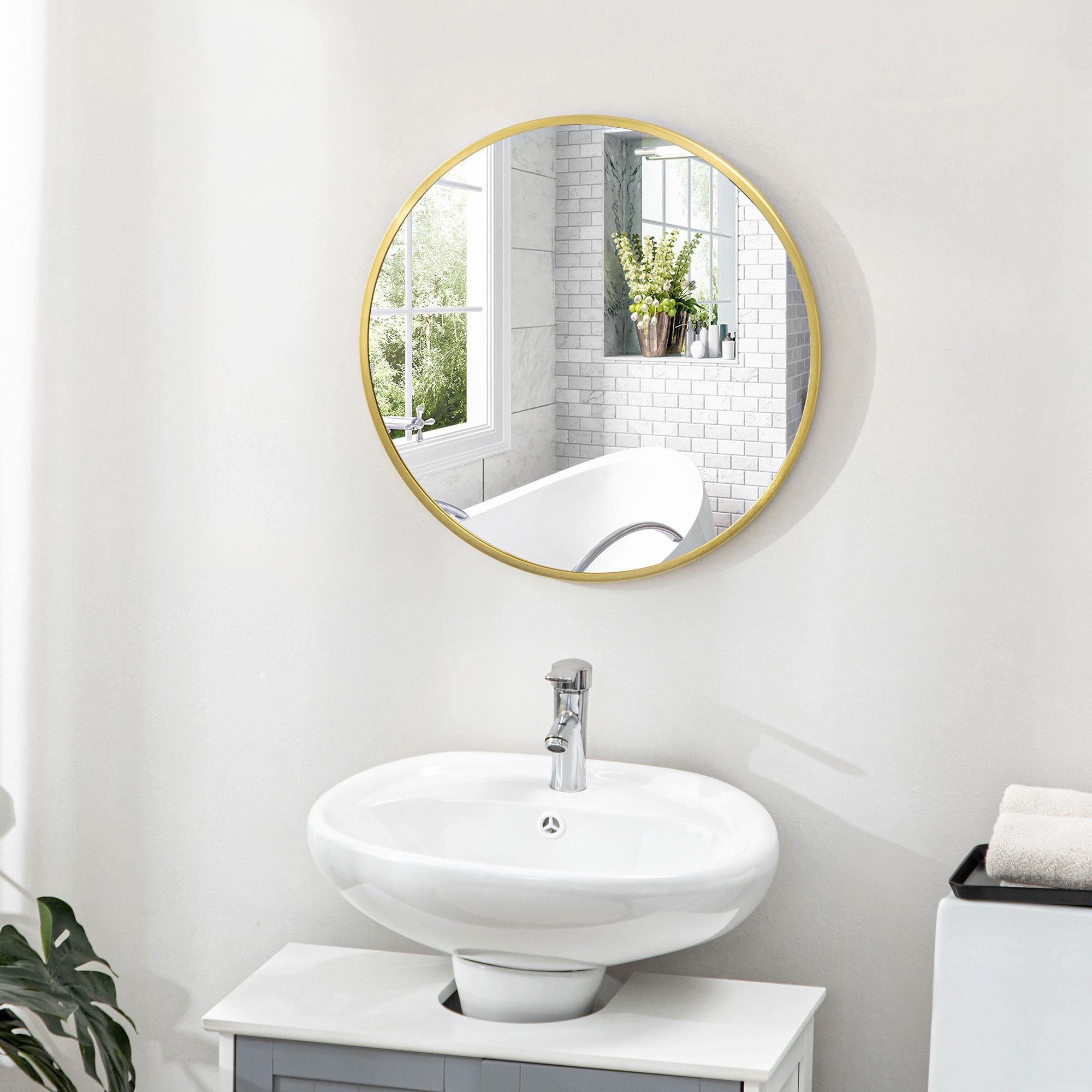 Badezimmer mit rundem Spiegel mit goldenem Rahmen über einem weißen Waschbecken und Fenster.