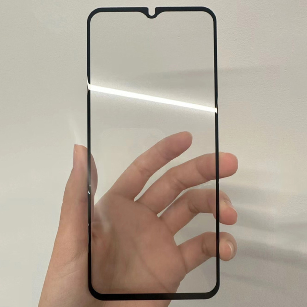 Una mano che tiene un proteggi schermo trasparente con una cornice nera.