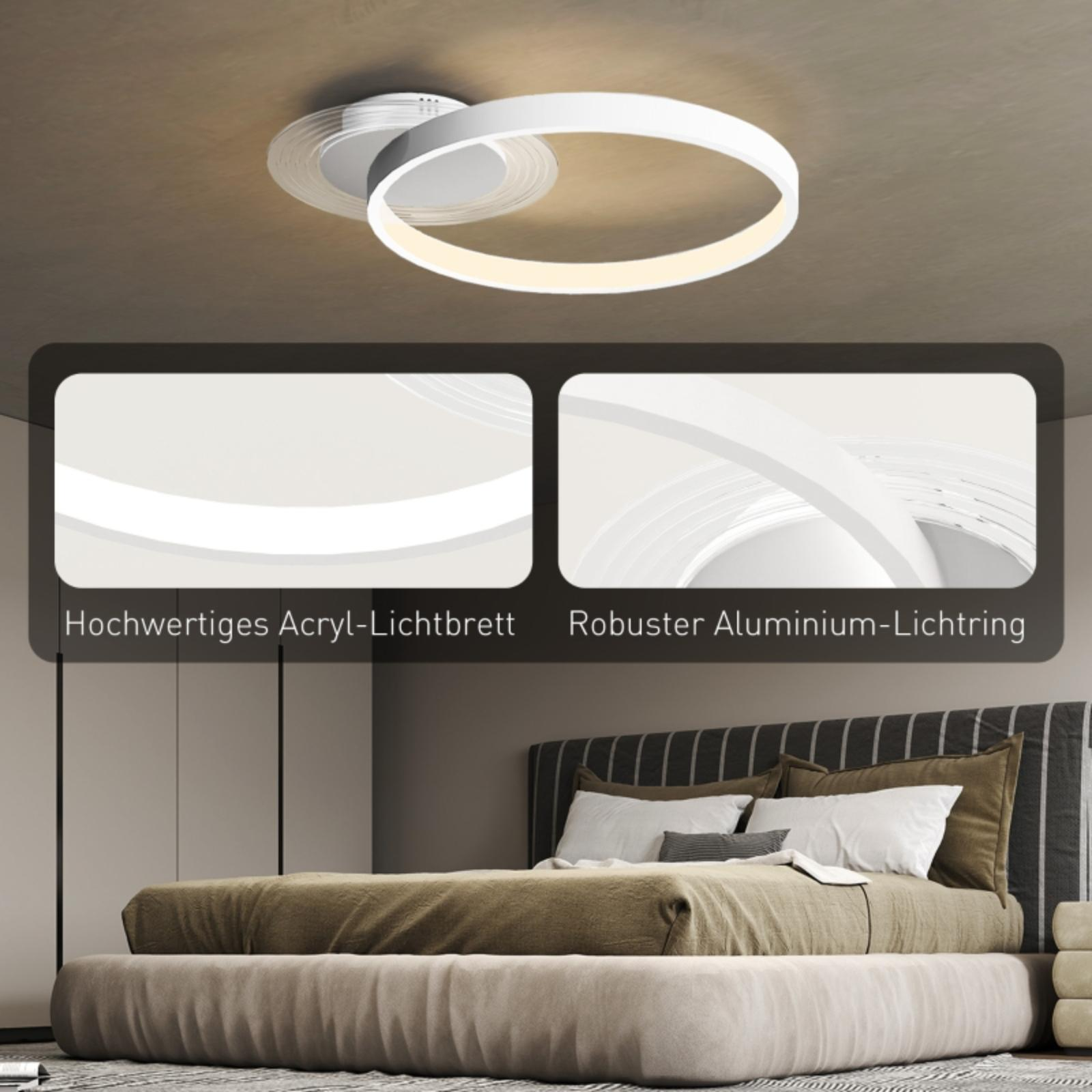 Weiße Deckenleuchte mit zwei miteinander verbundenen Ringen, mit einem Schlafzimmer im Hintergrund.
