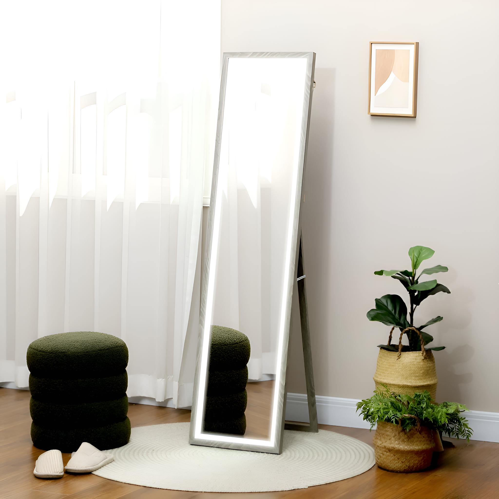 Ein hoher Spiegel mit LED-Leuchten, ein weicher Teppich und zwei grüne Sitzhocker.