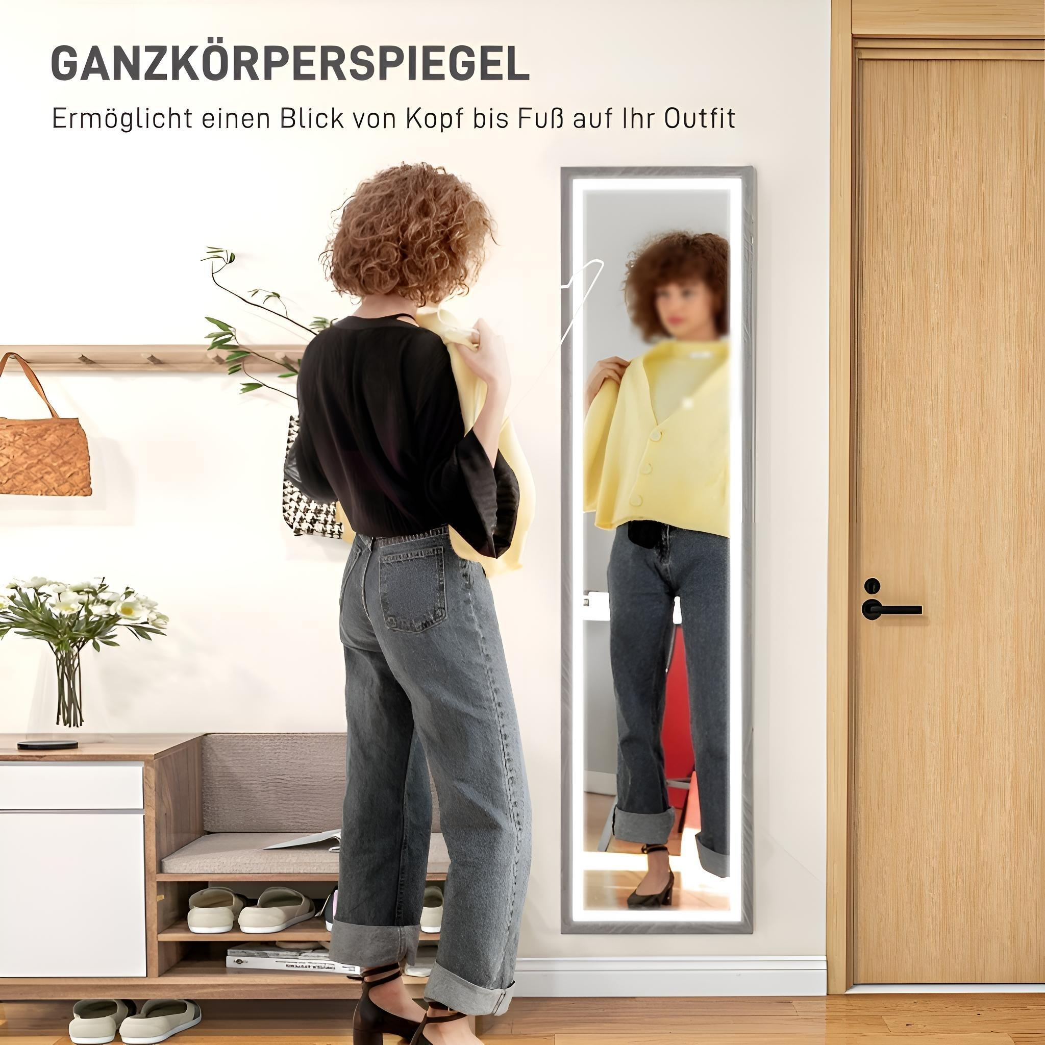 Eine Frau vor einem beleuchteten Ganzkörperspiegel, die ihre Reflexion in einem Raum betrachtet.
