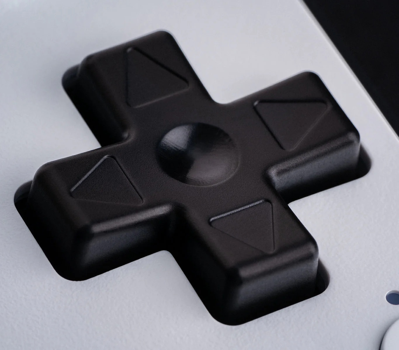 Zbliżenie czarnego D-padu na białym kontrolerze, pokazujące jego kształt krzyża.