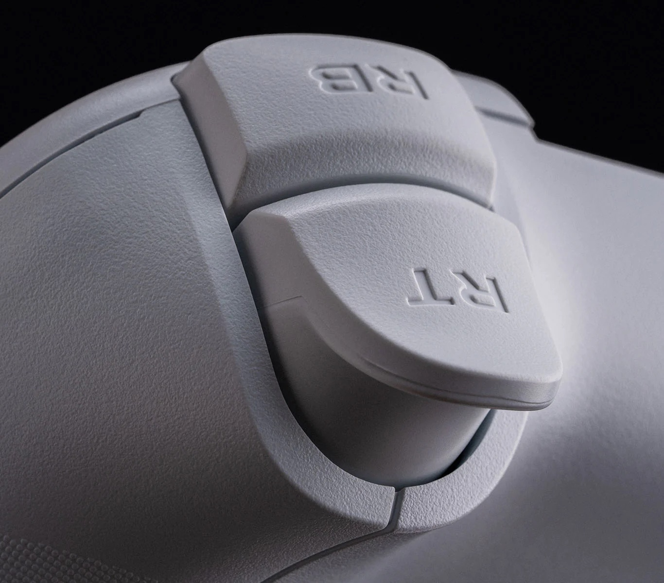 Zbliżenie szarych spustów kontrolera z etykietami 'RB' i 'RT'.