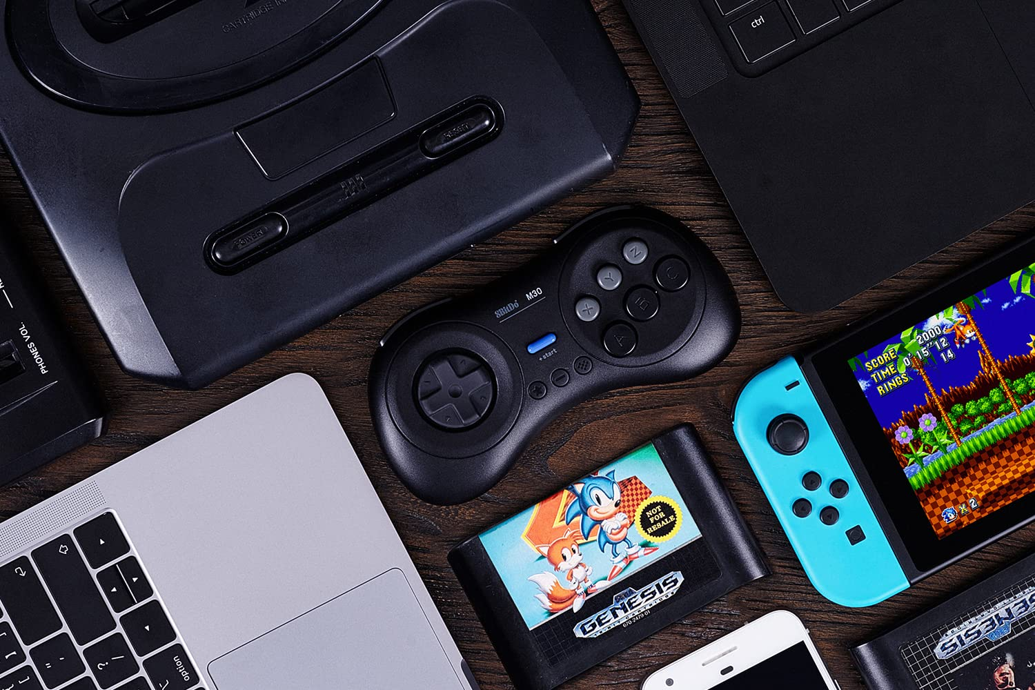 Un ordinateur portable, une console Switch, une manette et une cartouche sont sur une table.