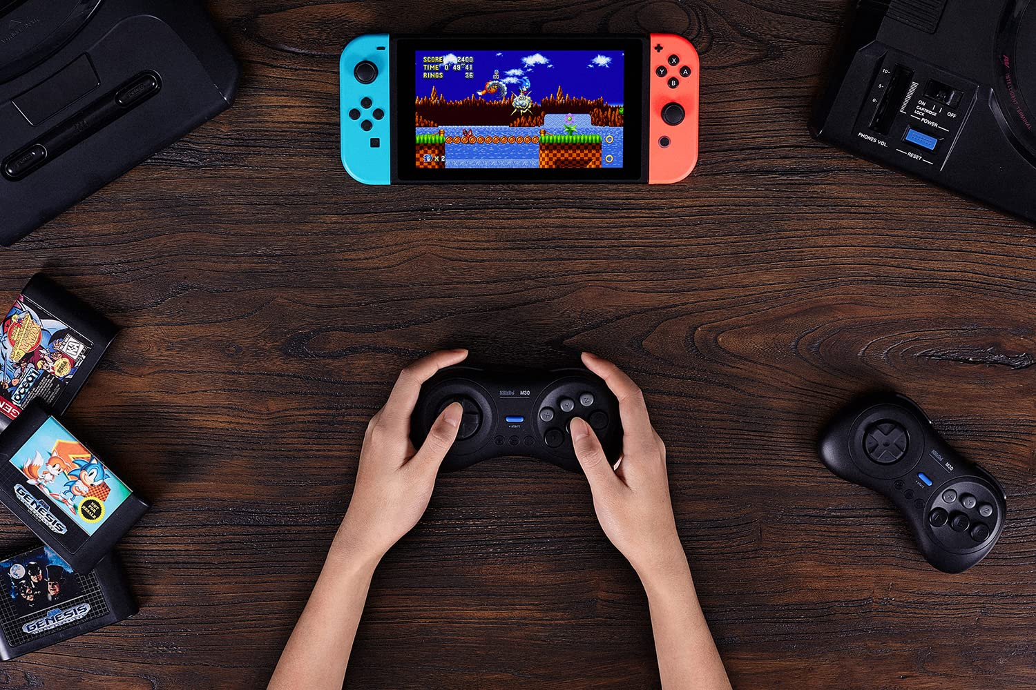 Mains tenant une manette noire jouant à un jeu sur une Nintendo Switch, entourée de cartouches.