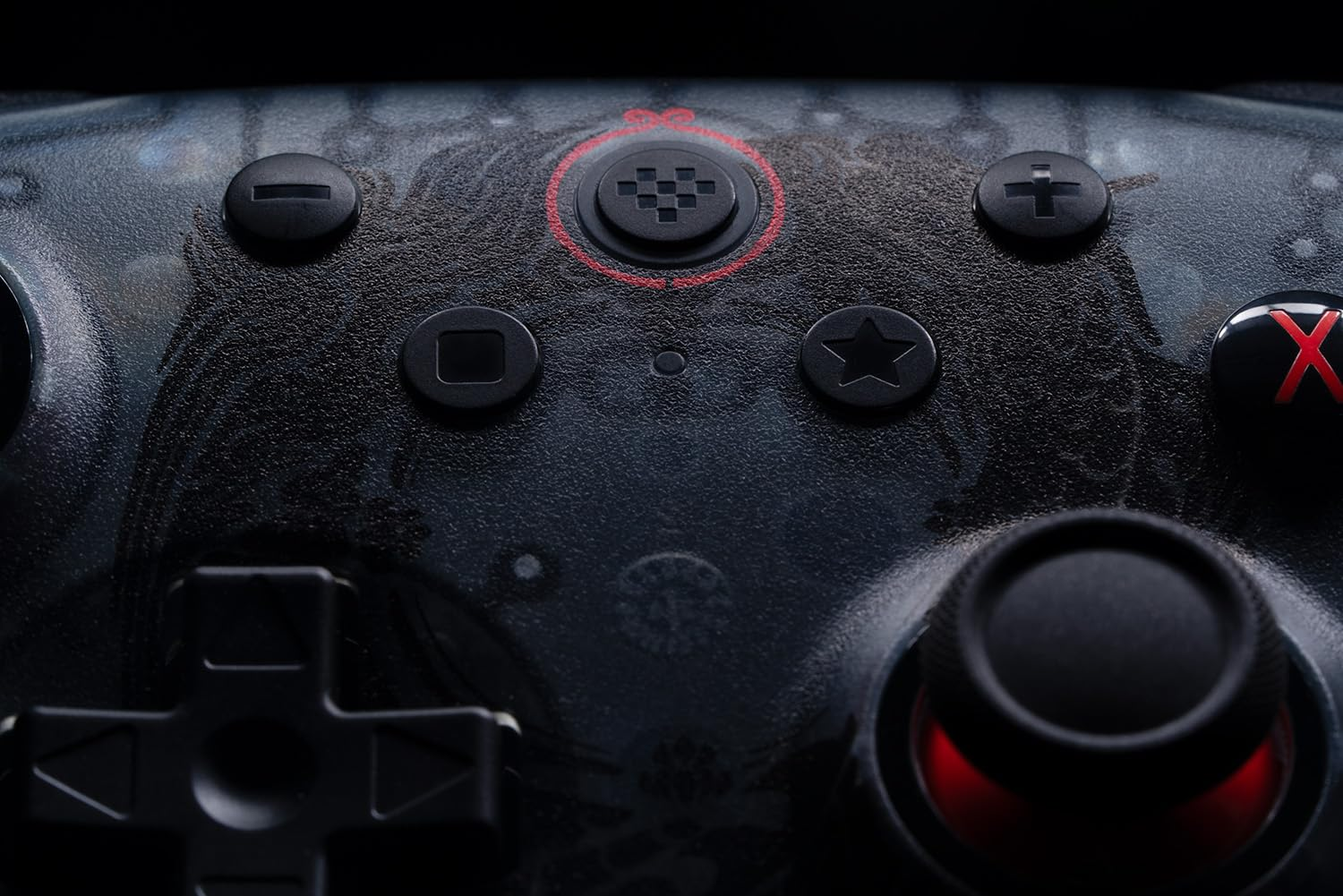Zbliżenie przycisków kontrolera do gier. Przyciski obejmują pad kierunkowy, start i X, z ciemnym tłem.