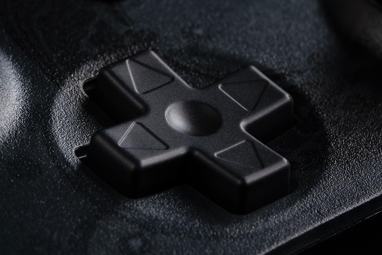 Zbliżenie na pad kierunkowy czarnego kontrolera. Pad ma kształt krzyża i jest czarny.