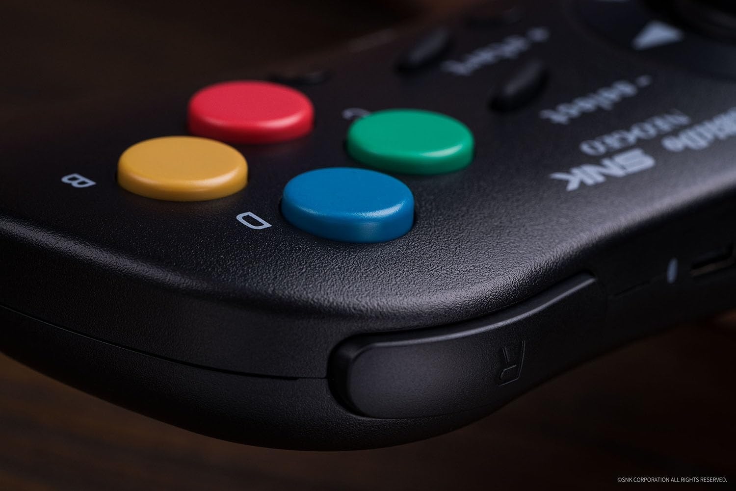 Zbliżenie przycisków czarnego gamepada: czerwony, żółty, zielony i niebieski. To retro design.