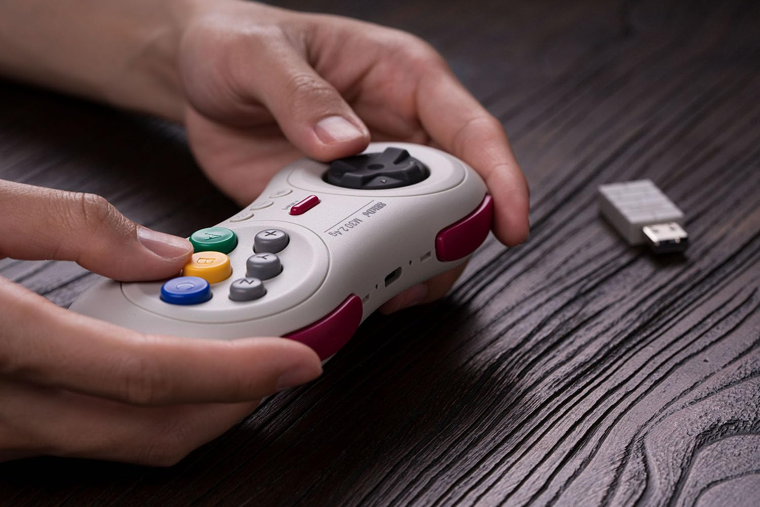Una persona tiene un controller tra le mani. Il controller ha pulsanti colorati.