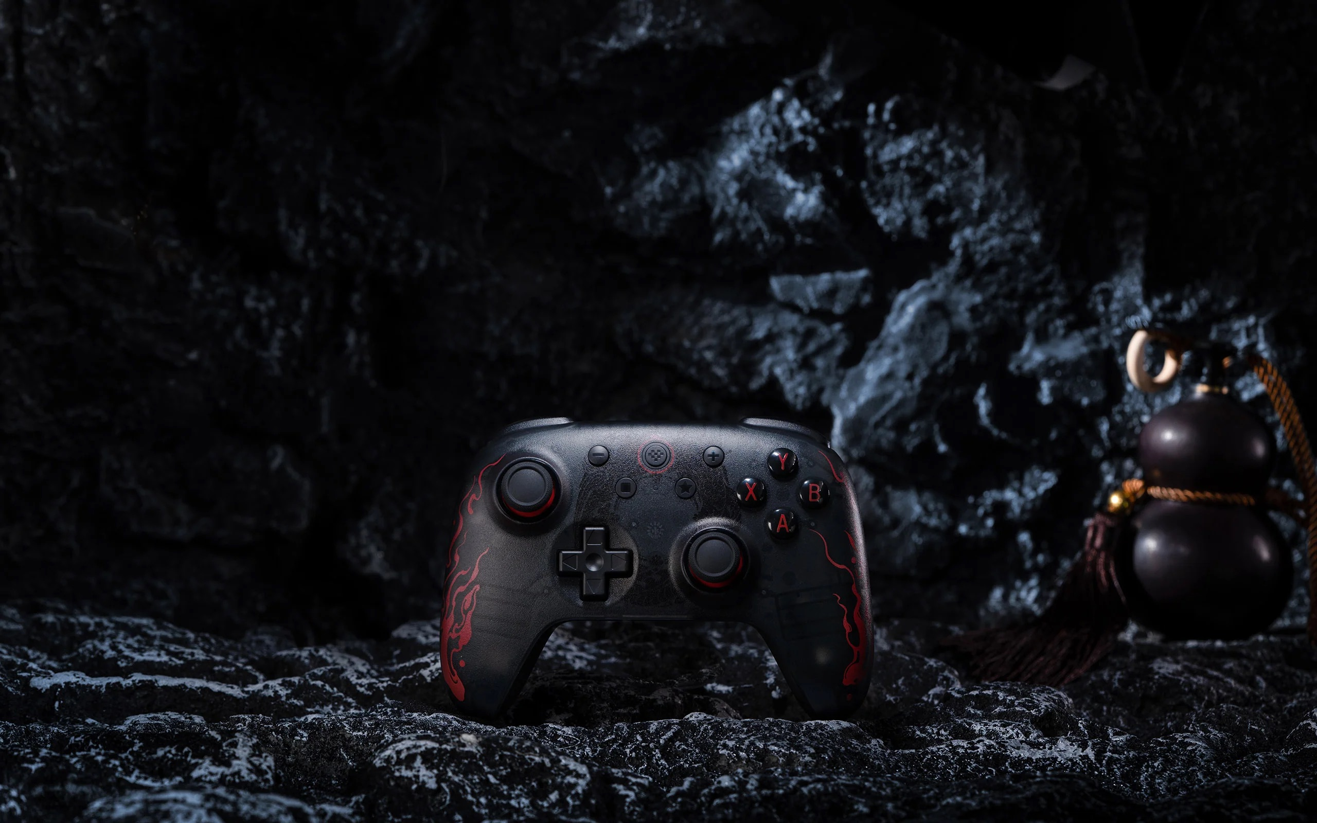 Czarny kontroler z czerwonymi akcentami umieszczony na ciemnej kamiennej powierzchni.