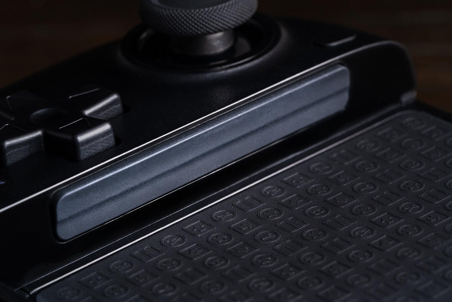 Zbliżenie czarnego kontrolera o teksturowanej powierzchni. Widoczny jest krzyżak i joystick.