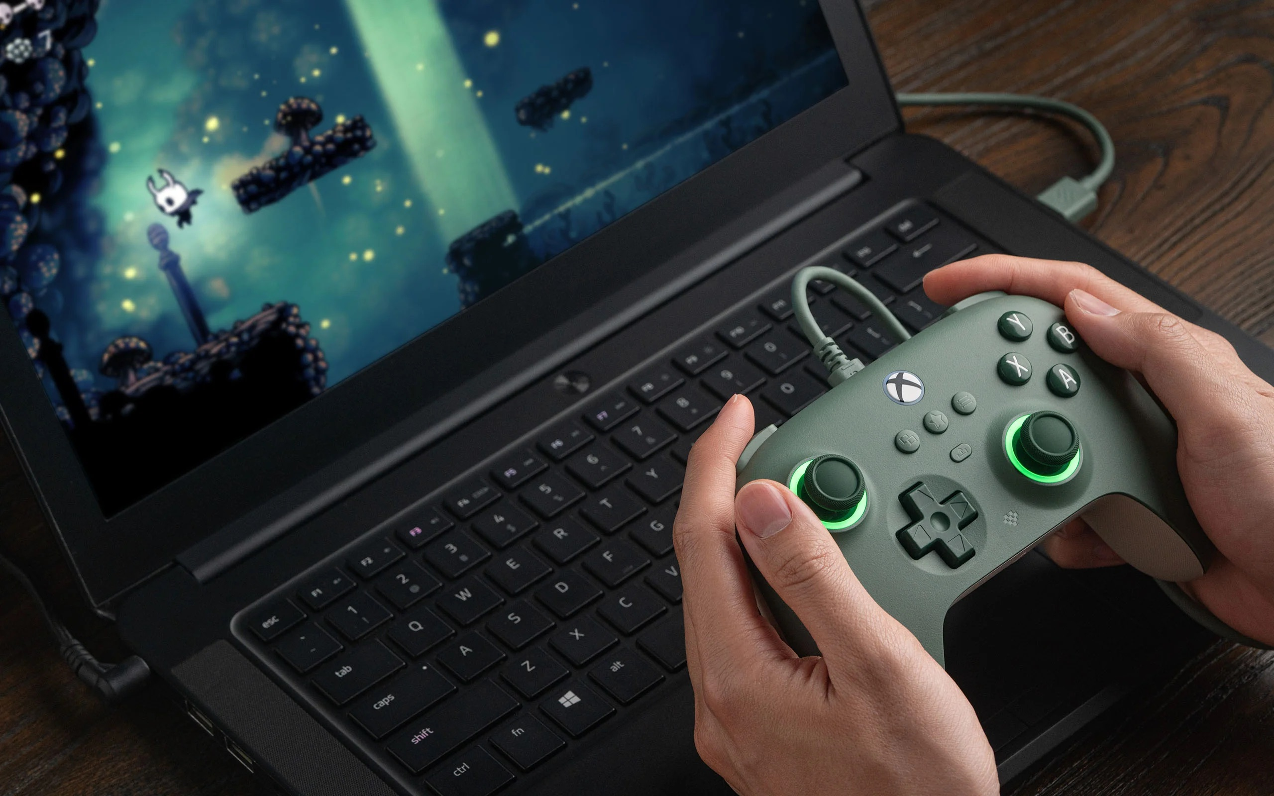 Una persona che gioca a un videogioco su un laptop con un controller verde.