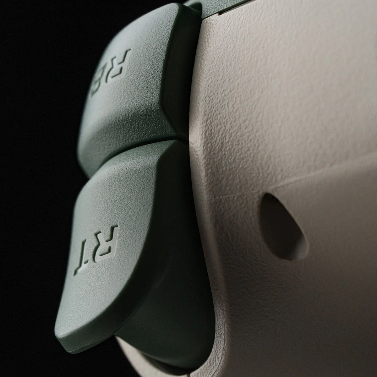 Primo piano dei pulsanti RT e RB su un controller di gioco verde e grigio.