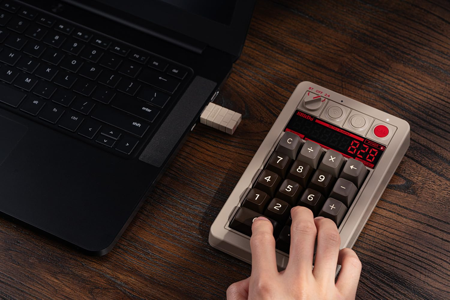 Osoba korzysta z retro klawiatury numerycznej podłączonej do laptopa. Wyświetlacz pokazuje 828.