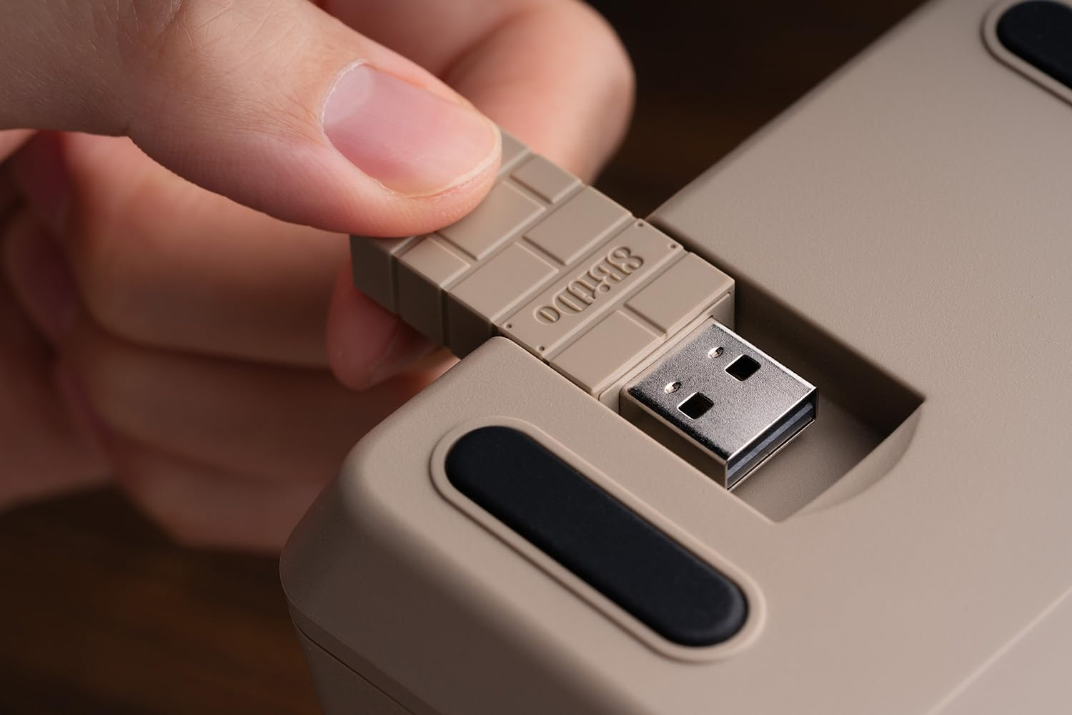 Ręka wkładająca beżowy odbiornik USB do pasującego kolorystycznie kalkulatora.