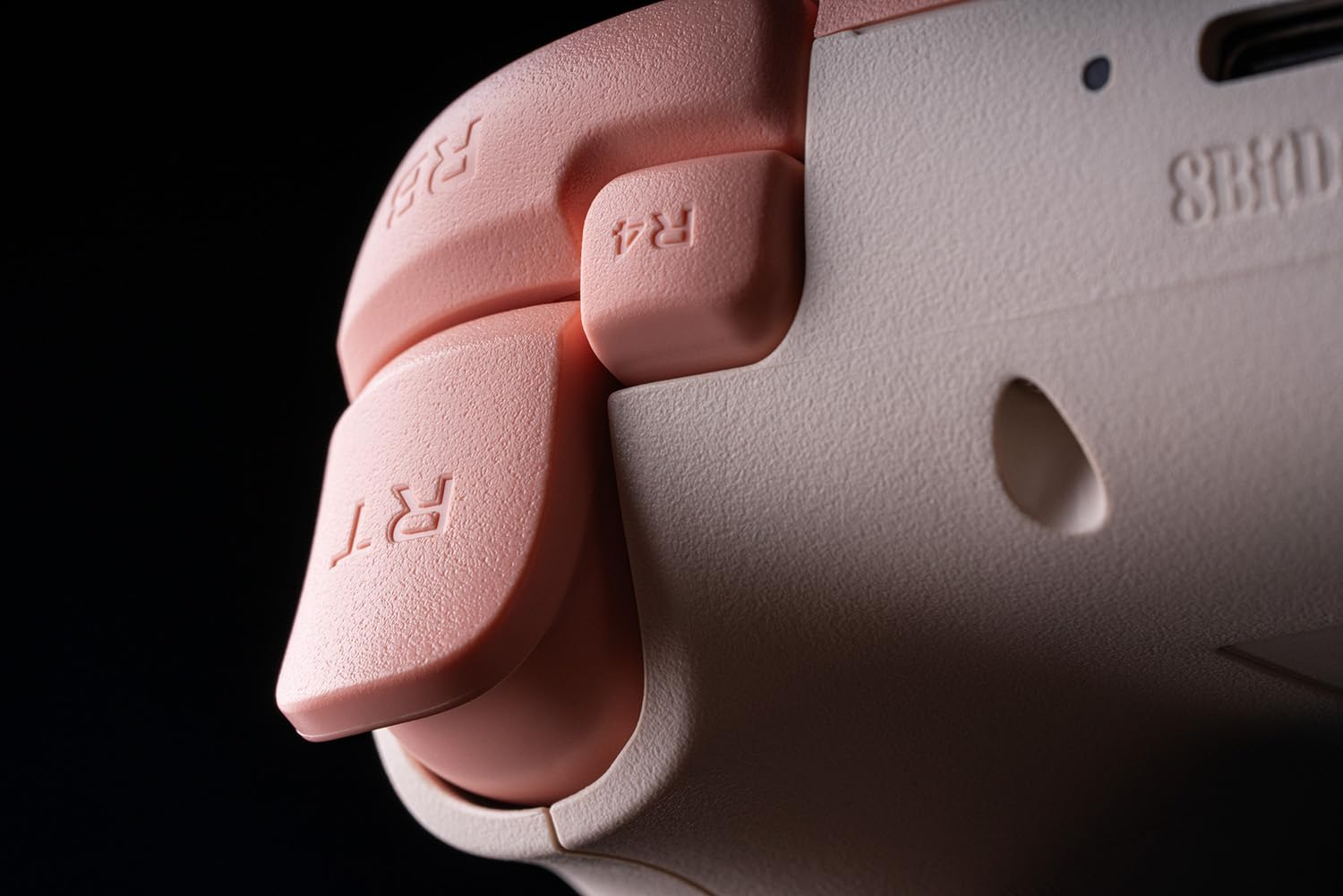 Zbliżenie kontrolera Xbox z różowymi przyciskami i spustami. Tło jest czarne.