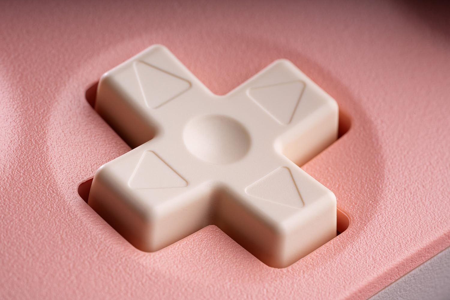 Zbliżenie krzyżakowego pada kierunkowego różowego kontrolera do gier. Pad jest kremowy.