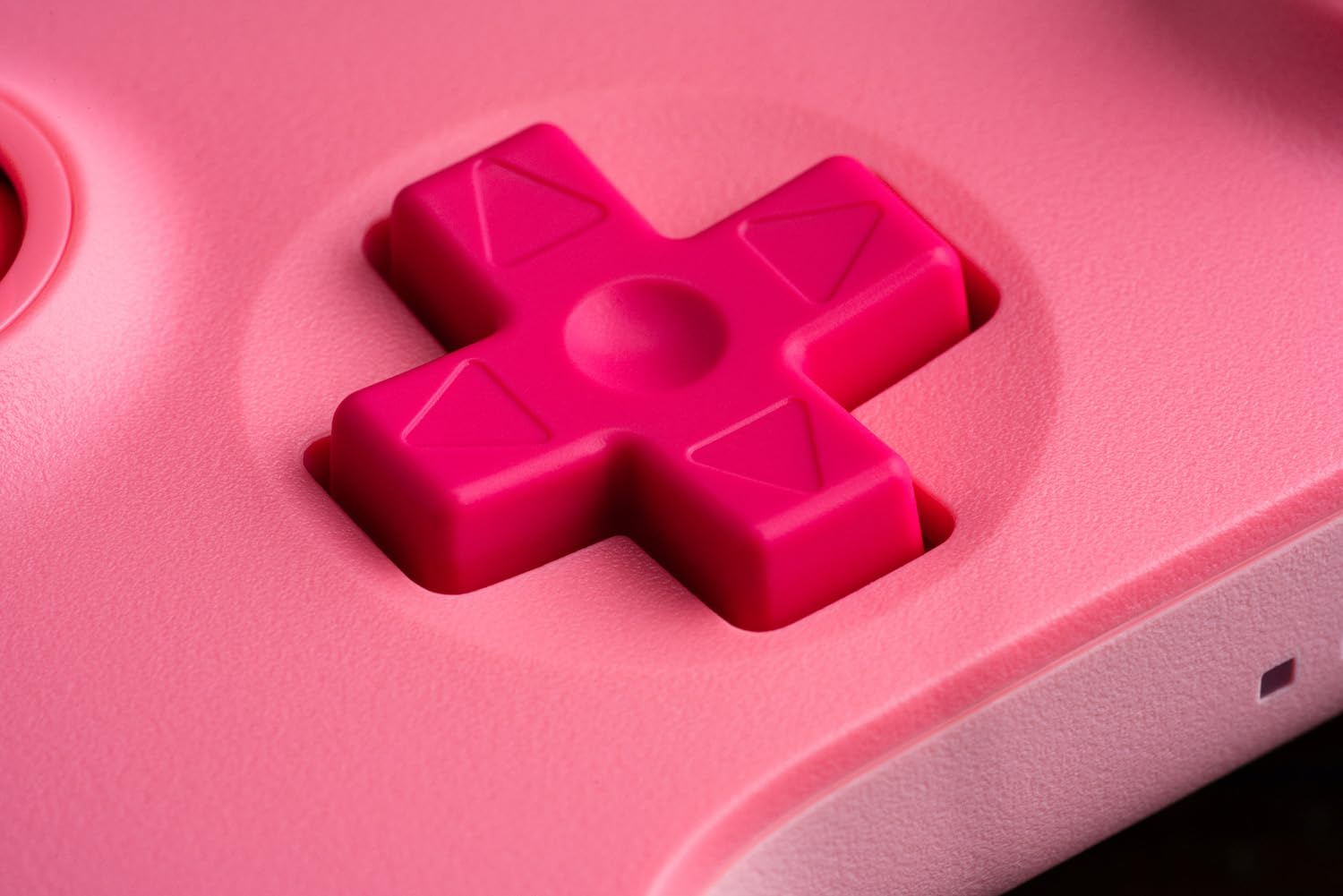 Zbliżenie krzyżaka kontrolera do gier w kolorze różowym. Pad ma kształt jasnoróżowego krzyża.