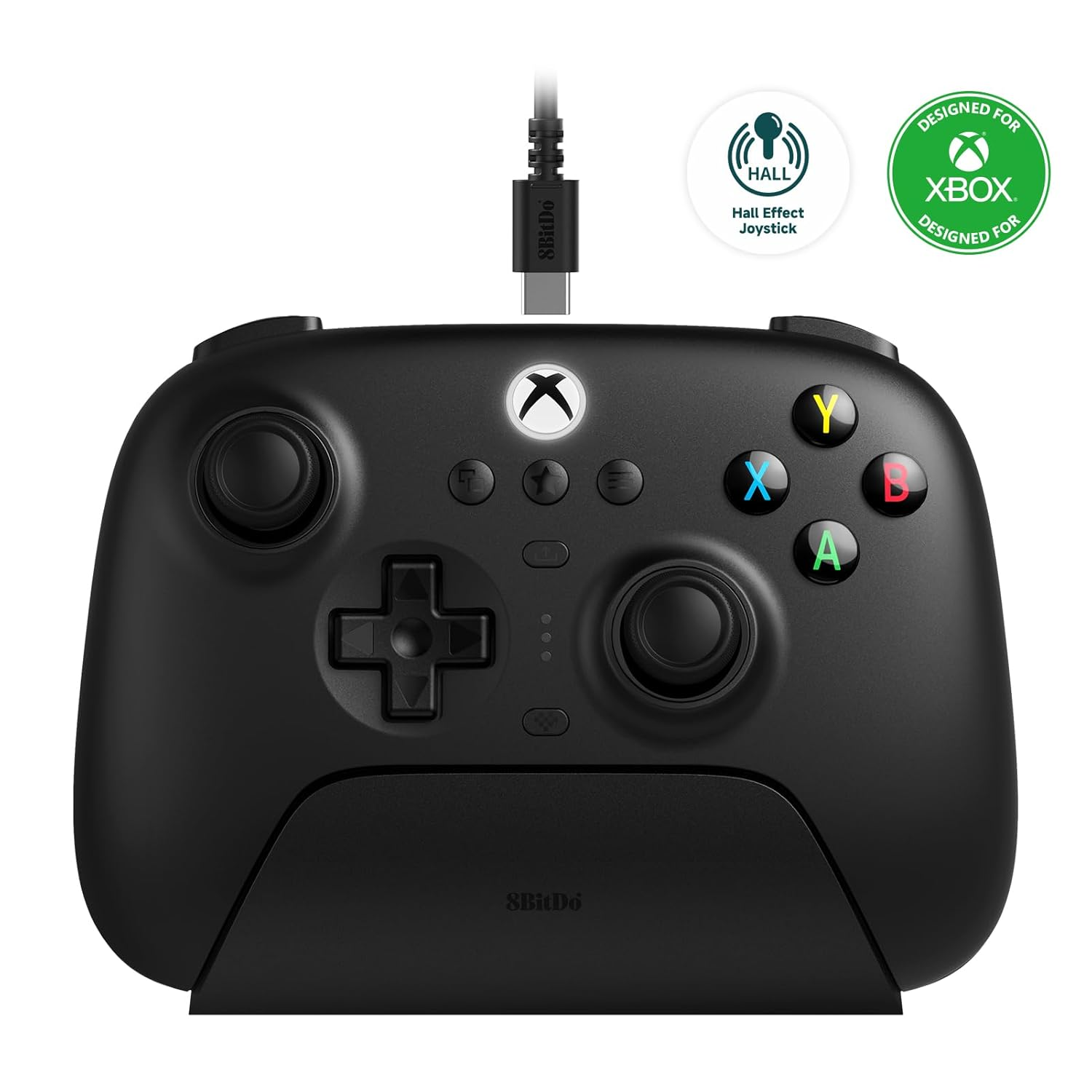 Un controller Xbox nero sul suo supporto di ricarica, con un cavo e loghi, su sfondo bianco.