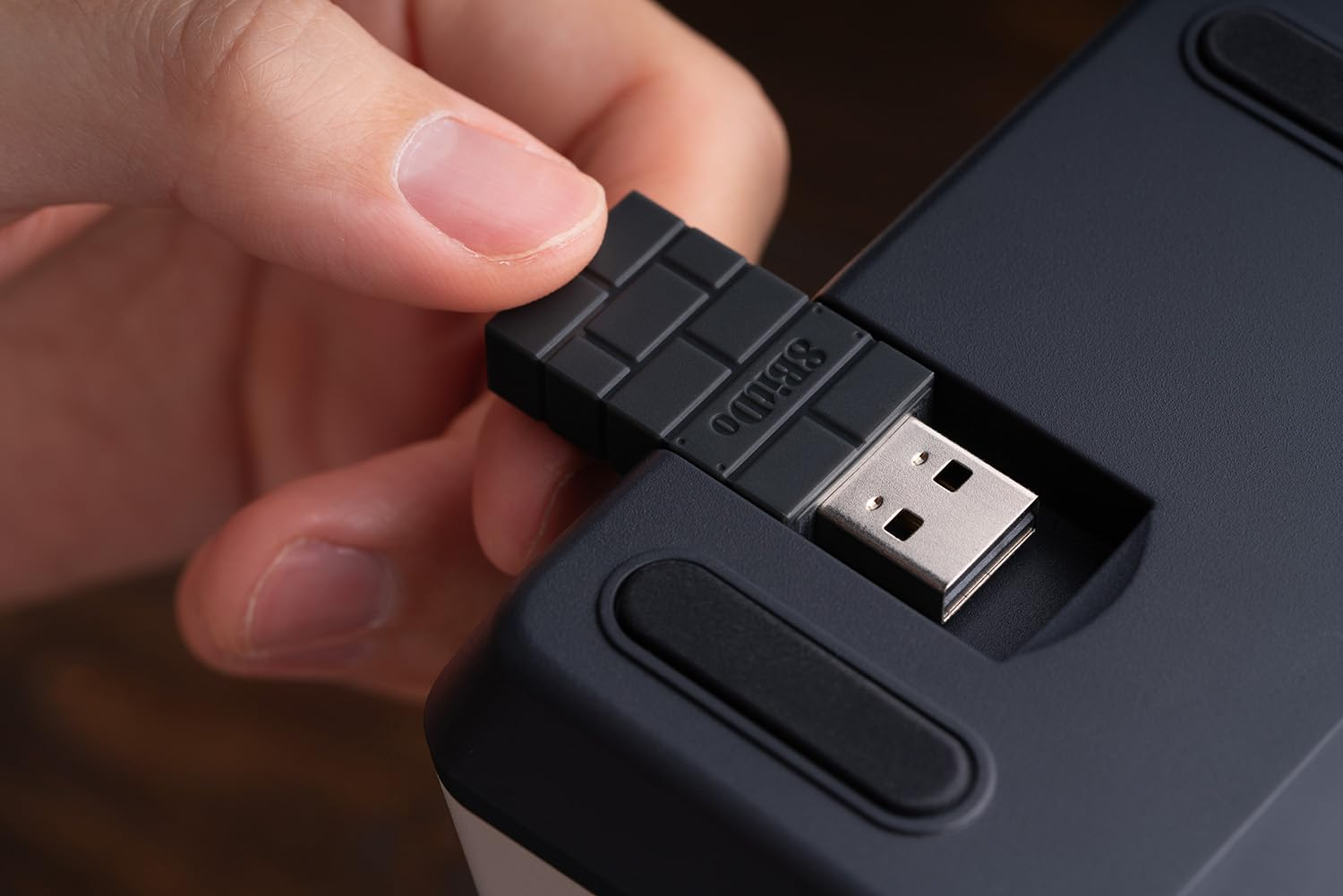 Ręka osoby wkłada odbiornik USB w dół urządzenia.