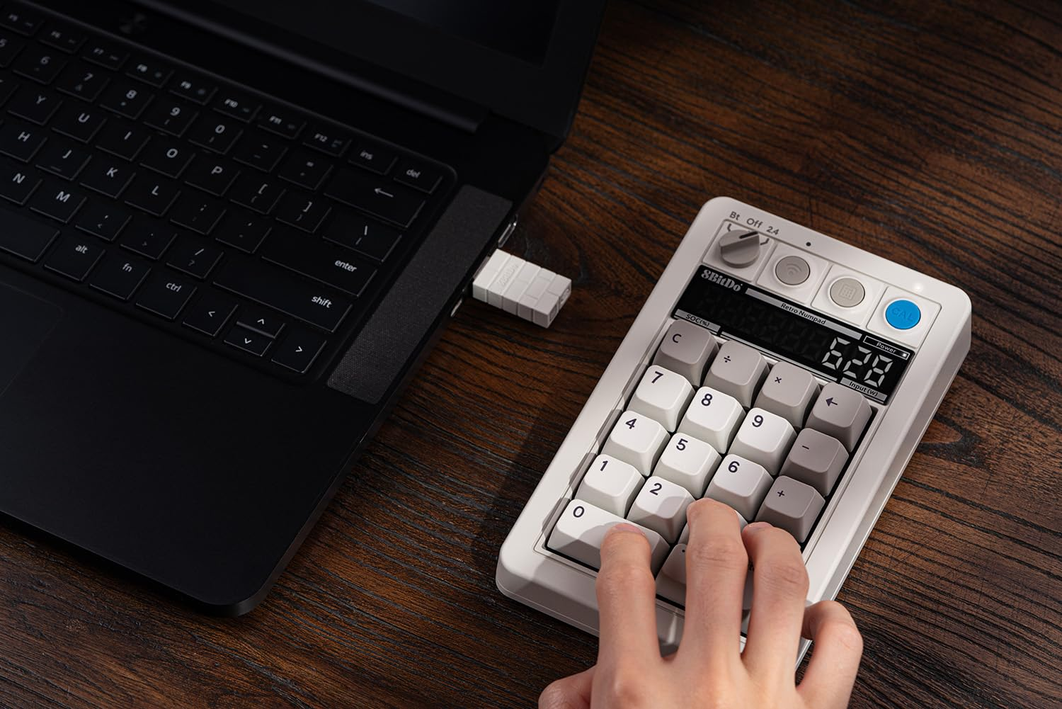Una persona usa un tastierino numerico retrò collegato a un laptop. Il tastierino numerico visualizza un numero.