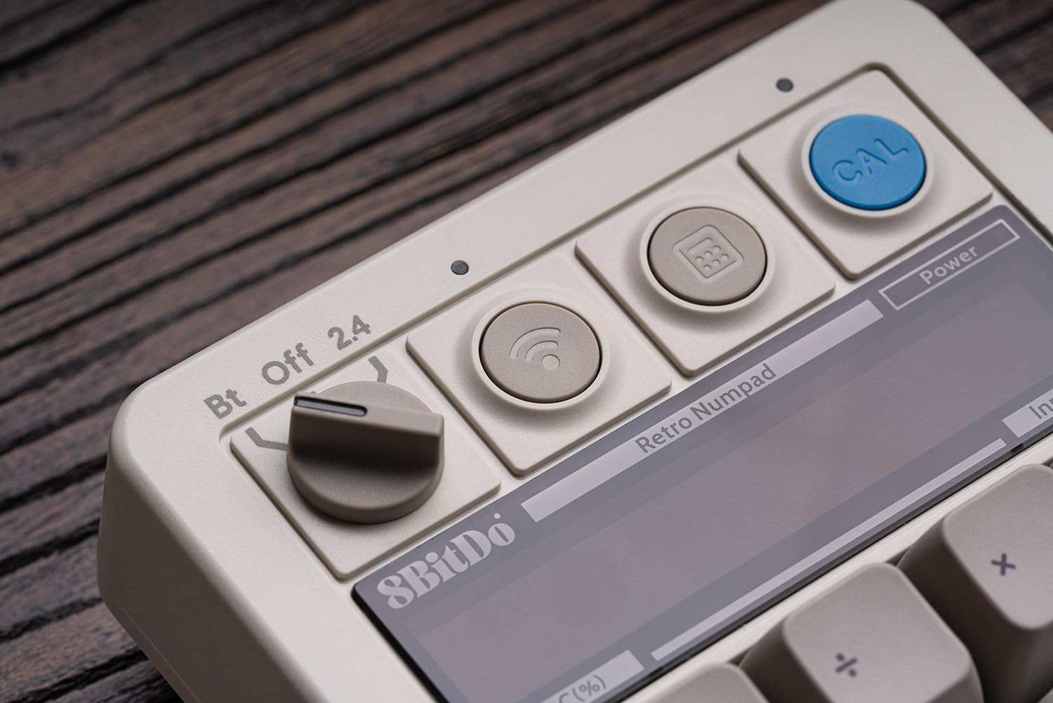 Un primo piano di un 8BitDo Retro Numpad bianco con pulsanti e un piccolo schermo.